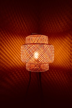 Woven bamboo lamp casting patterned light on wall