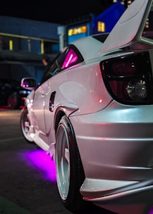 White sports car with purple underglow at night