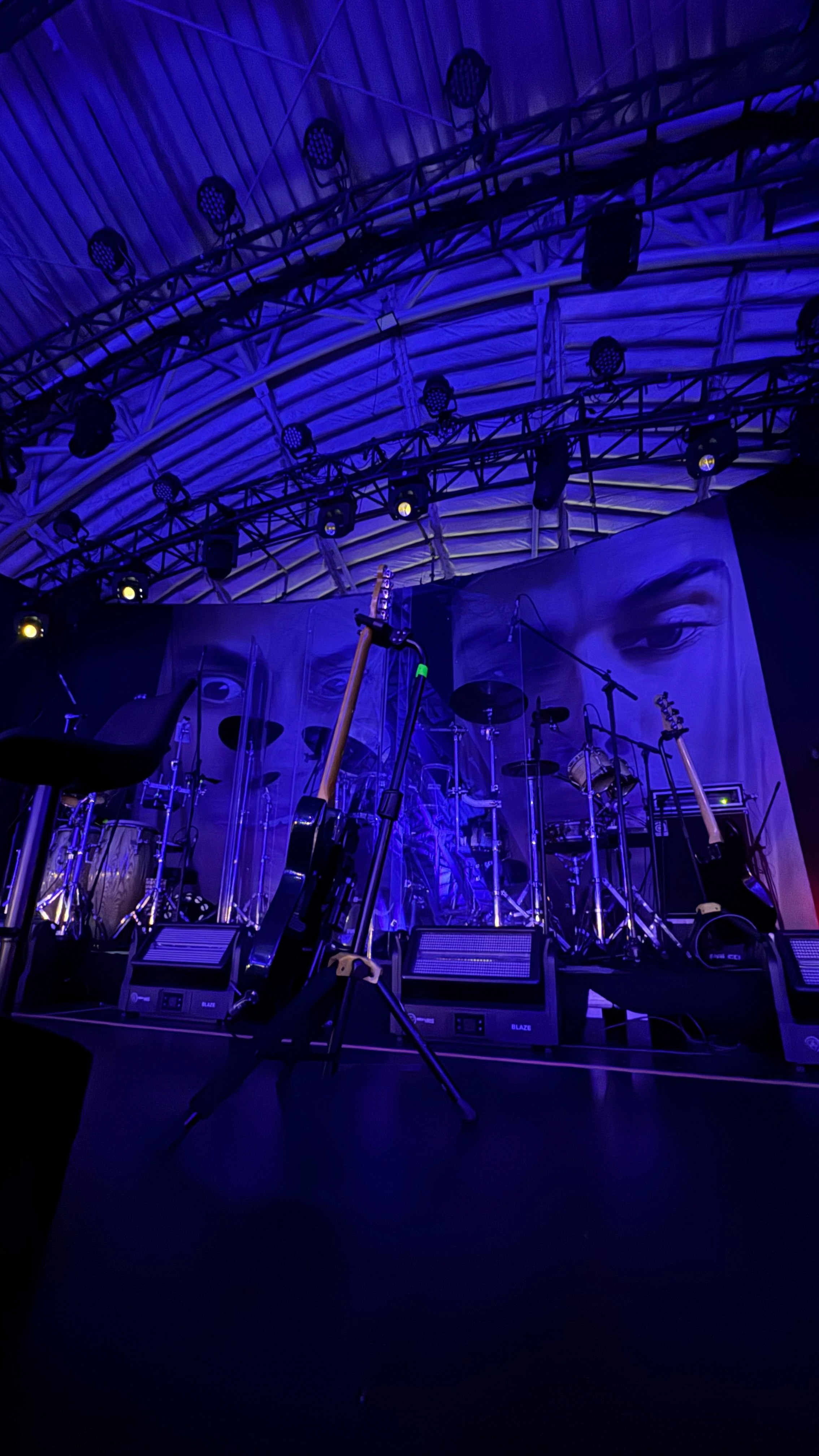 Stage with guitars and drum set under blue lights