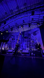 Stage with guitars and drum set under blue lights