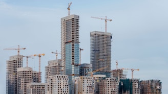 Skyscrapers under construction with cranes against sky.