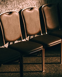 Row of empty brown leather chairs against wall