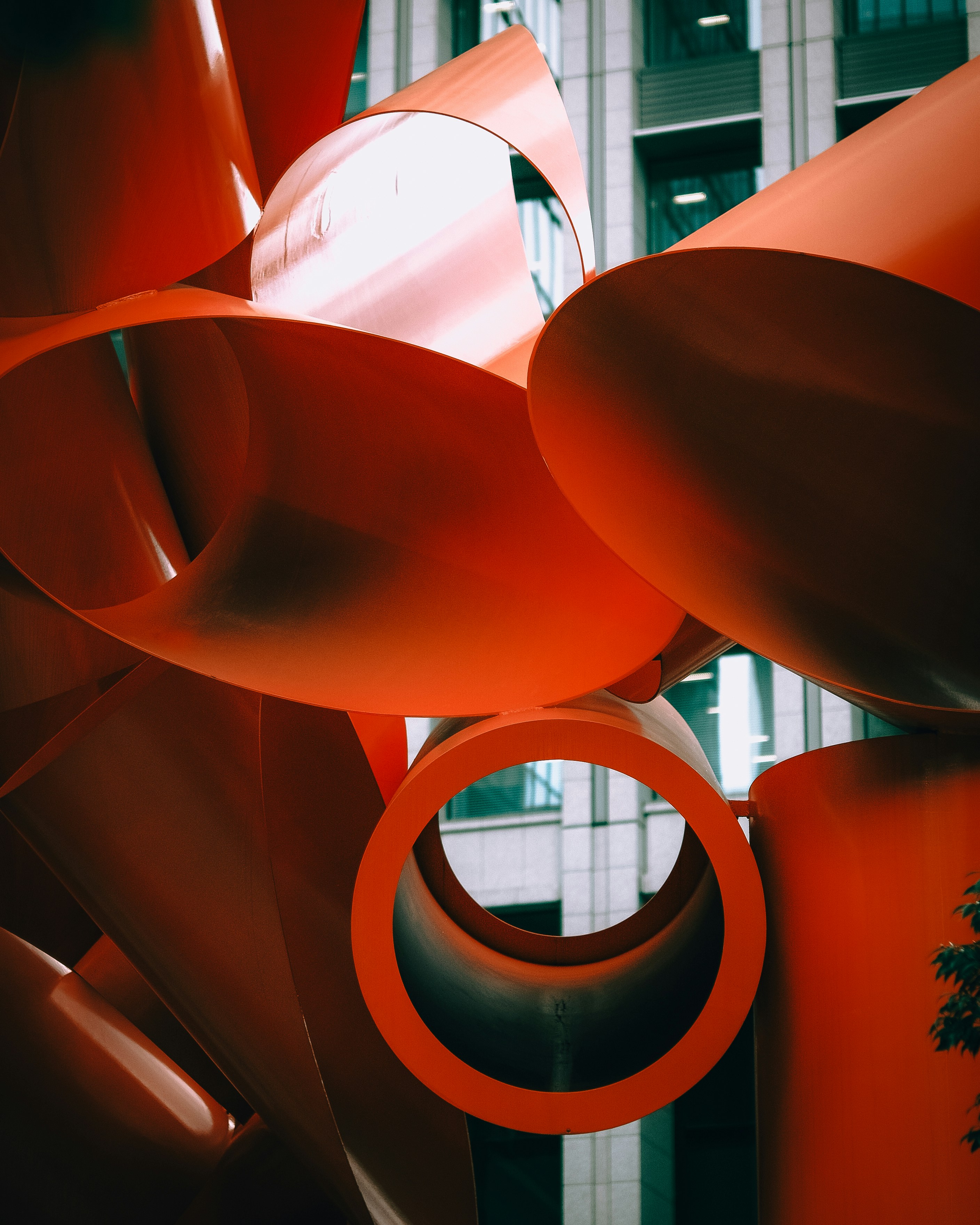 Abstrakte orangefarbene Skulptur vor einem modernen Gebäude