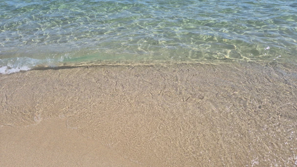 Clear ocean water washes onto a sandy beach shore.