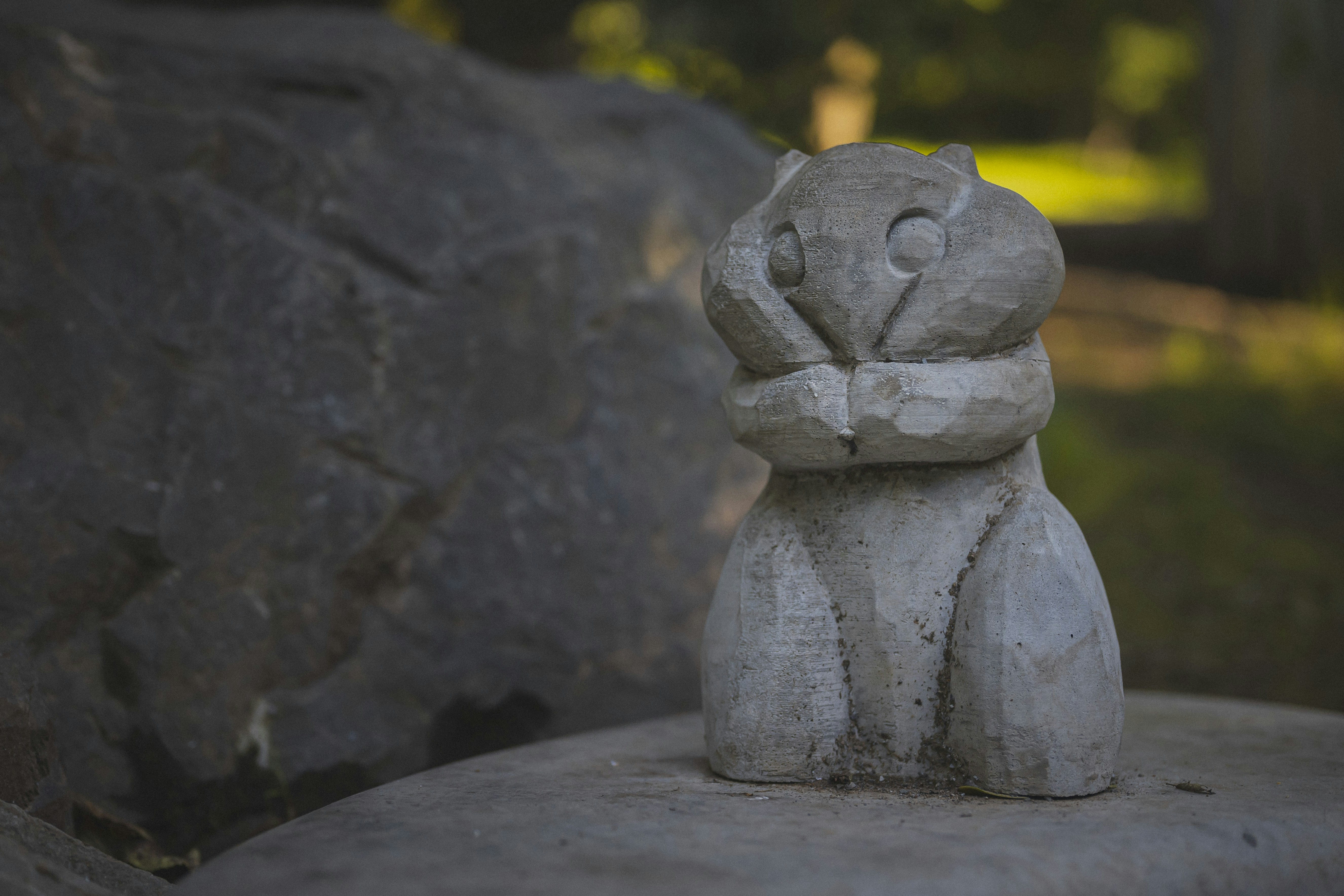 Eine hölzerne Eulenschnitzerei sitzt auf einem Felsen im Freien.