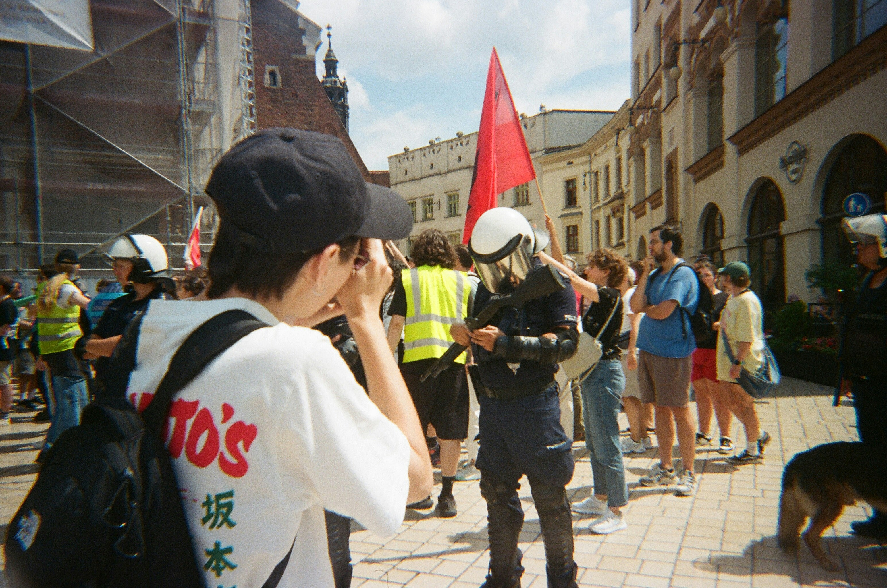 People gathered in a city square with a red flag.