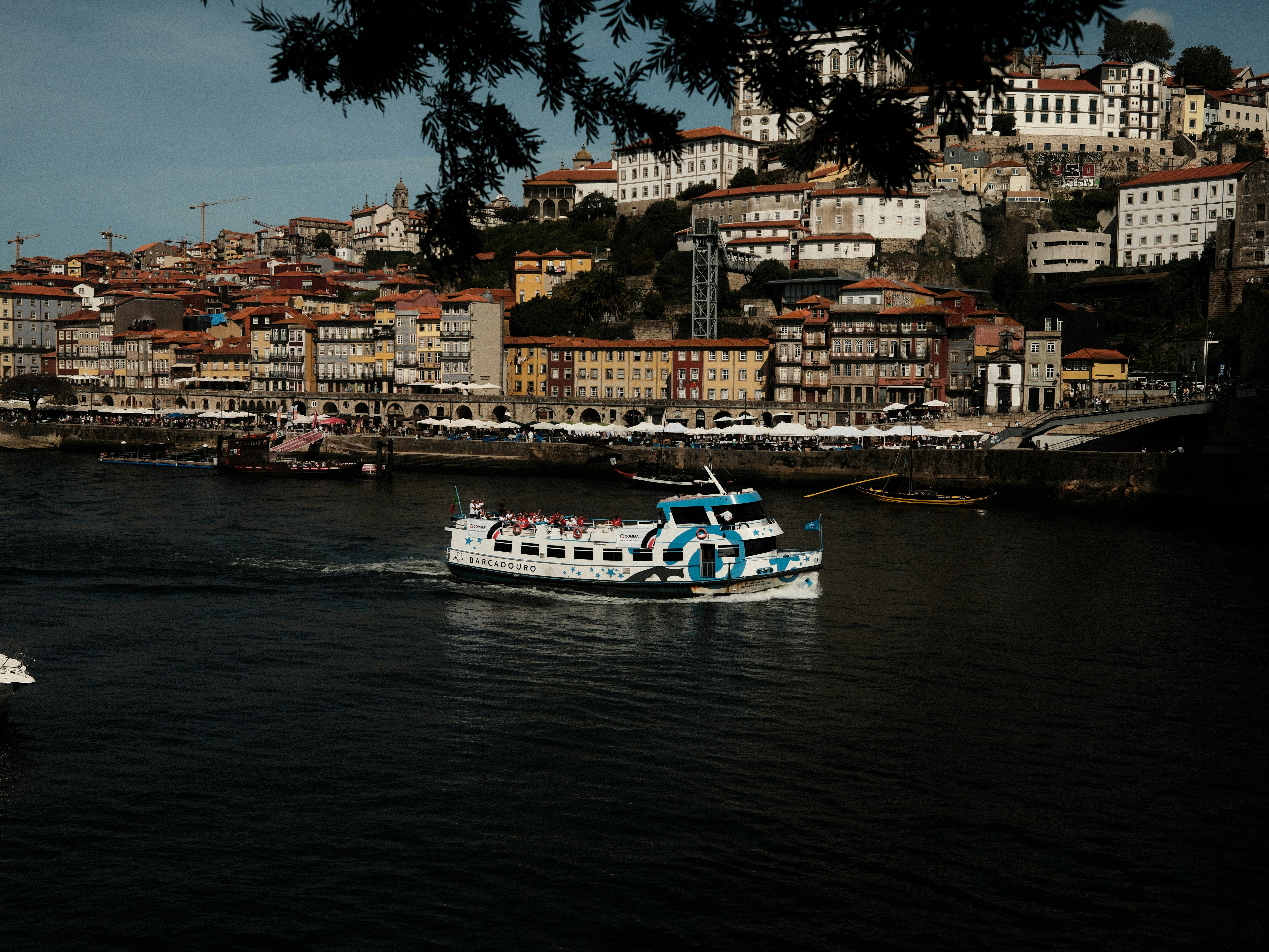 Boat sailing on a river with city buildings.