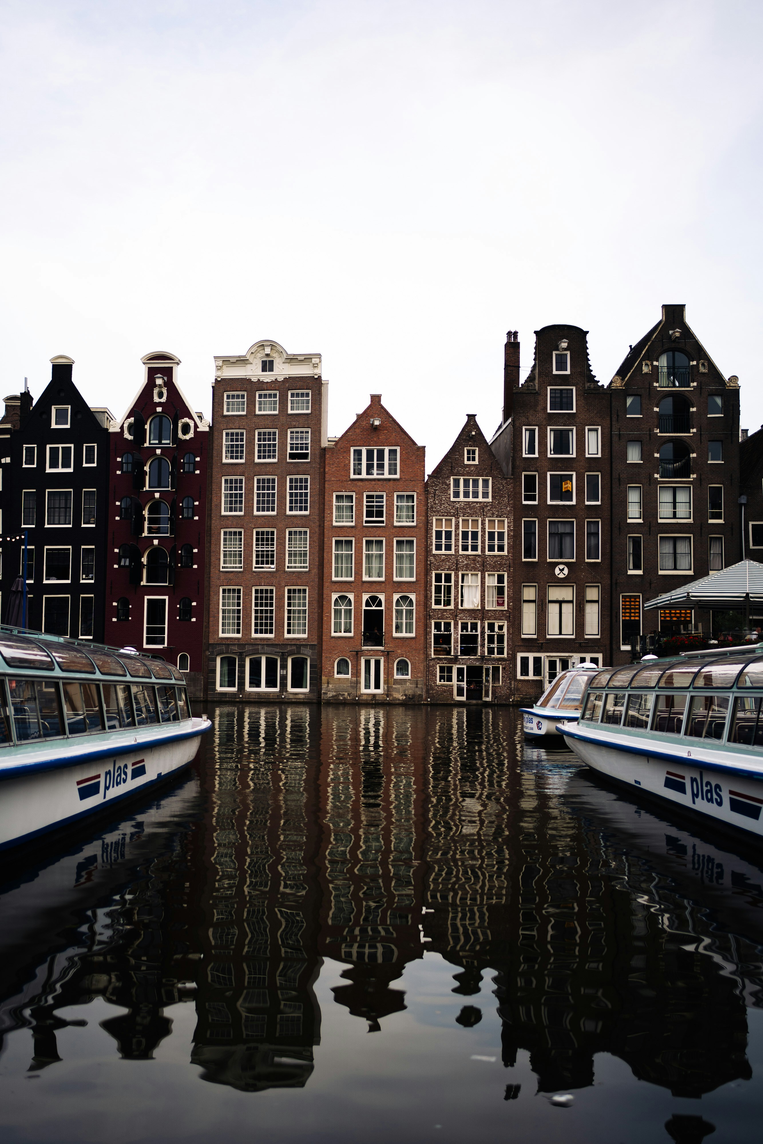 Canal houses reflected in water with tour boats