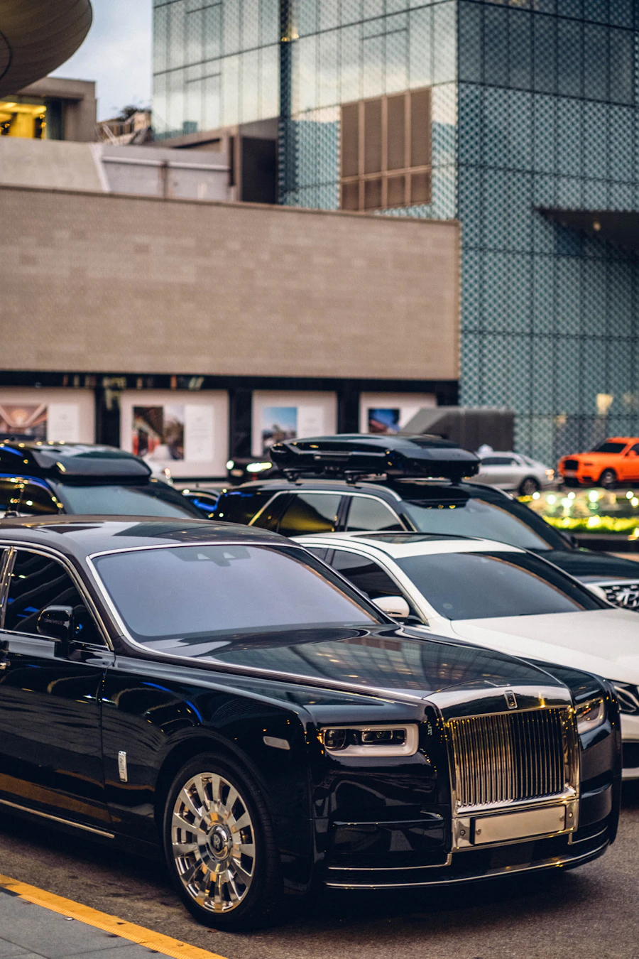 Luxury sedans including a Rolls-Royce parked on a city street