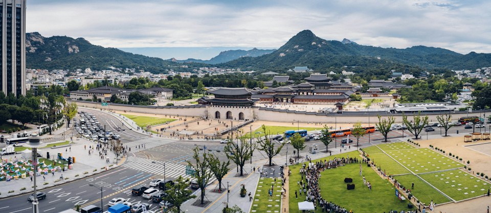 Gyeongbokgung Palace's stone gate with Bugaksan mountain rising behind it under a blue sky