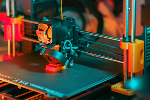 3D printer creating a red object with yellow filament.