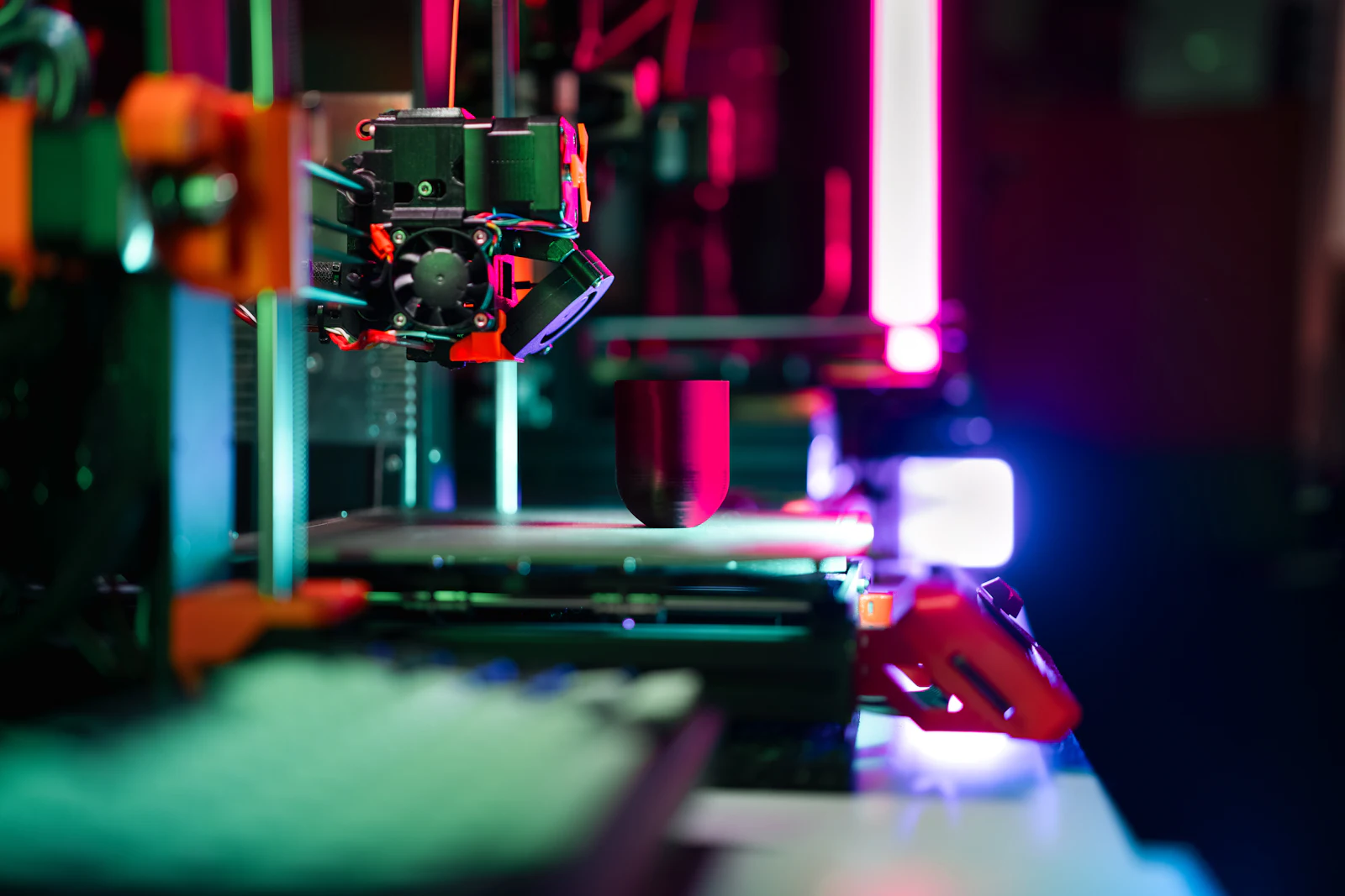 3D printer mid-print under neon lighting