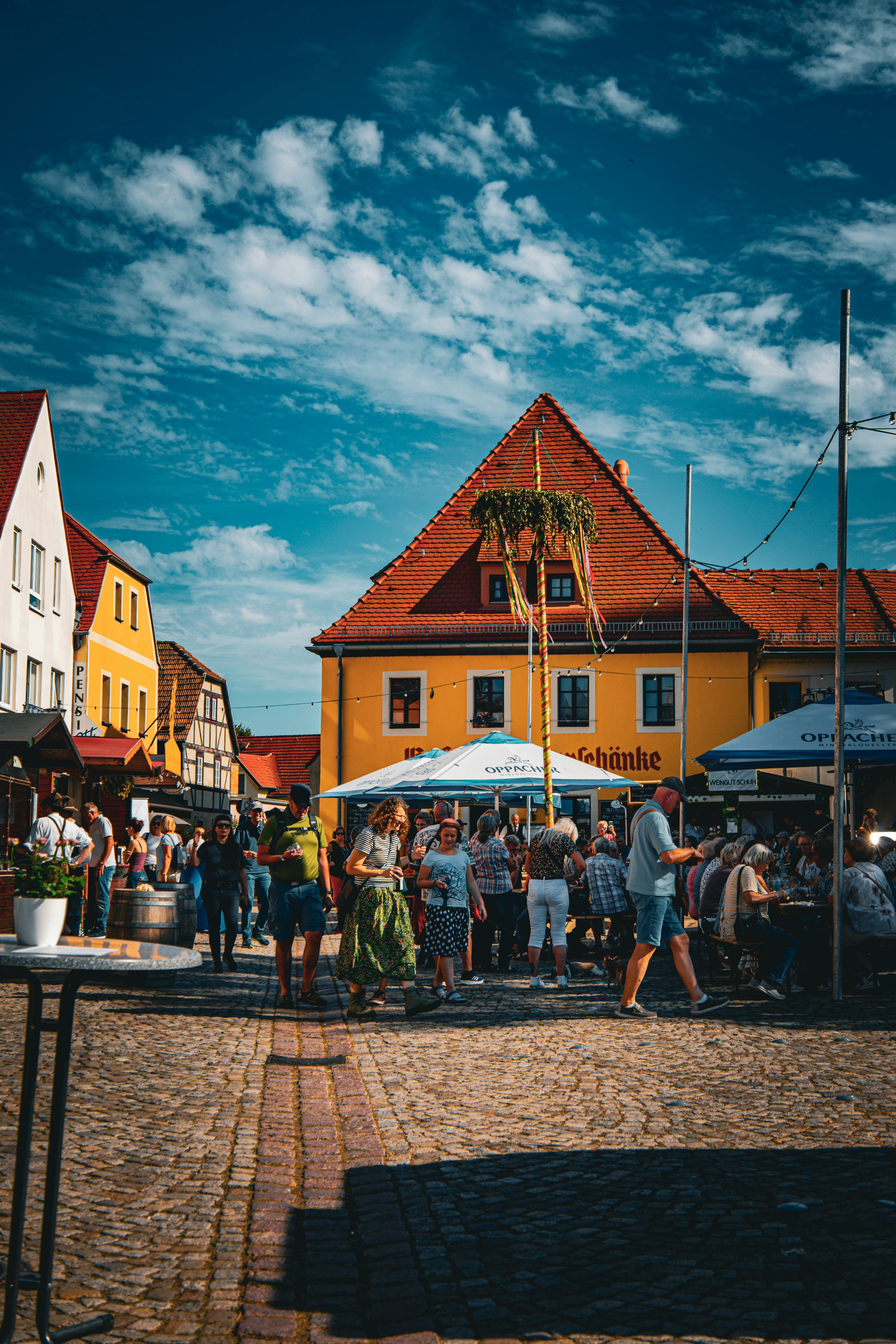 People gathered in a town square with buildings and stalls