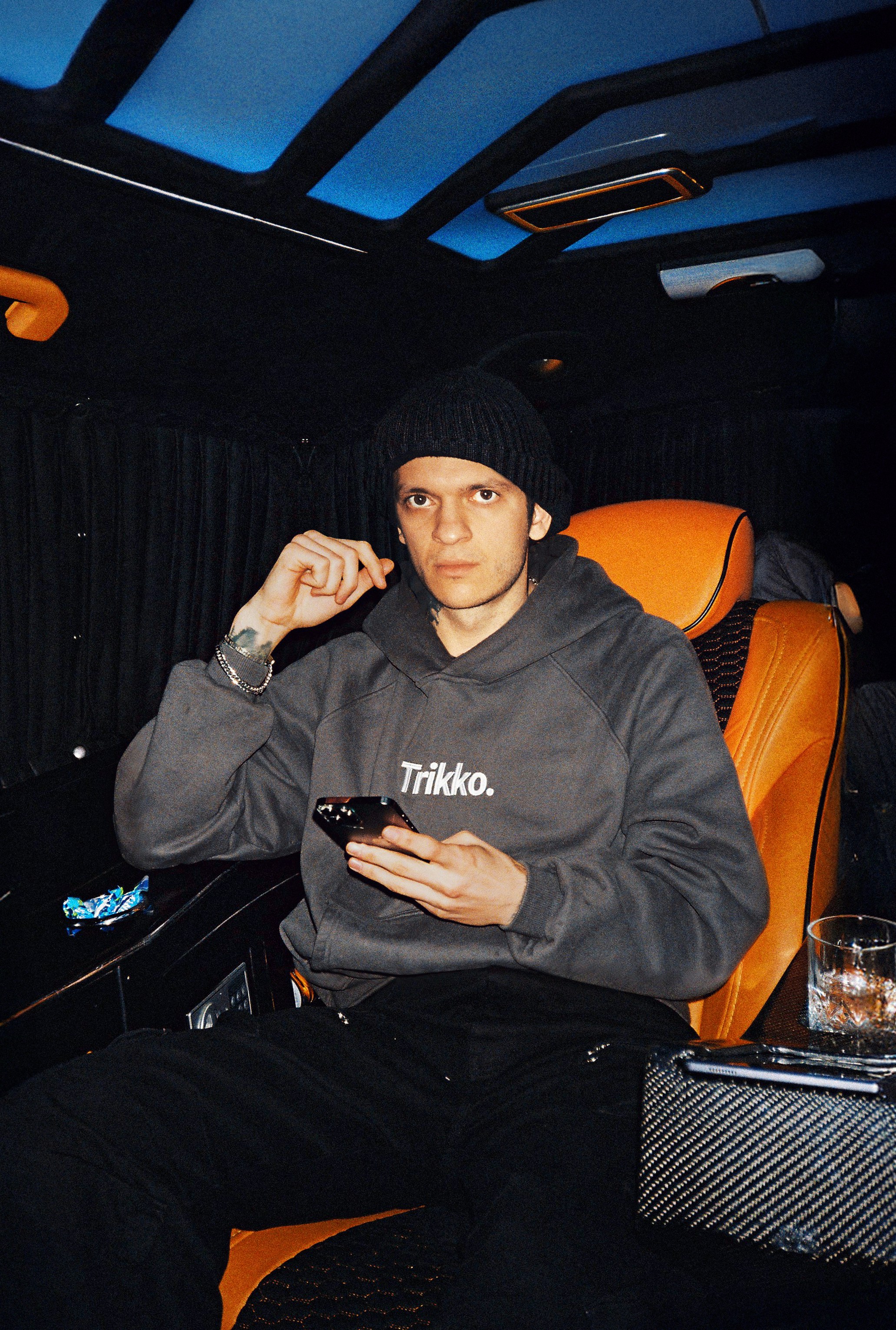 Man in beanie and hoodie holding phone in car