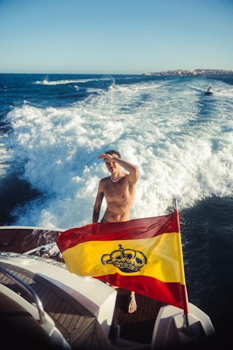 Man on boat with spanish flag enjoys ocean view