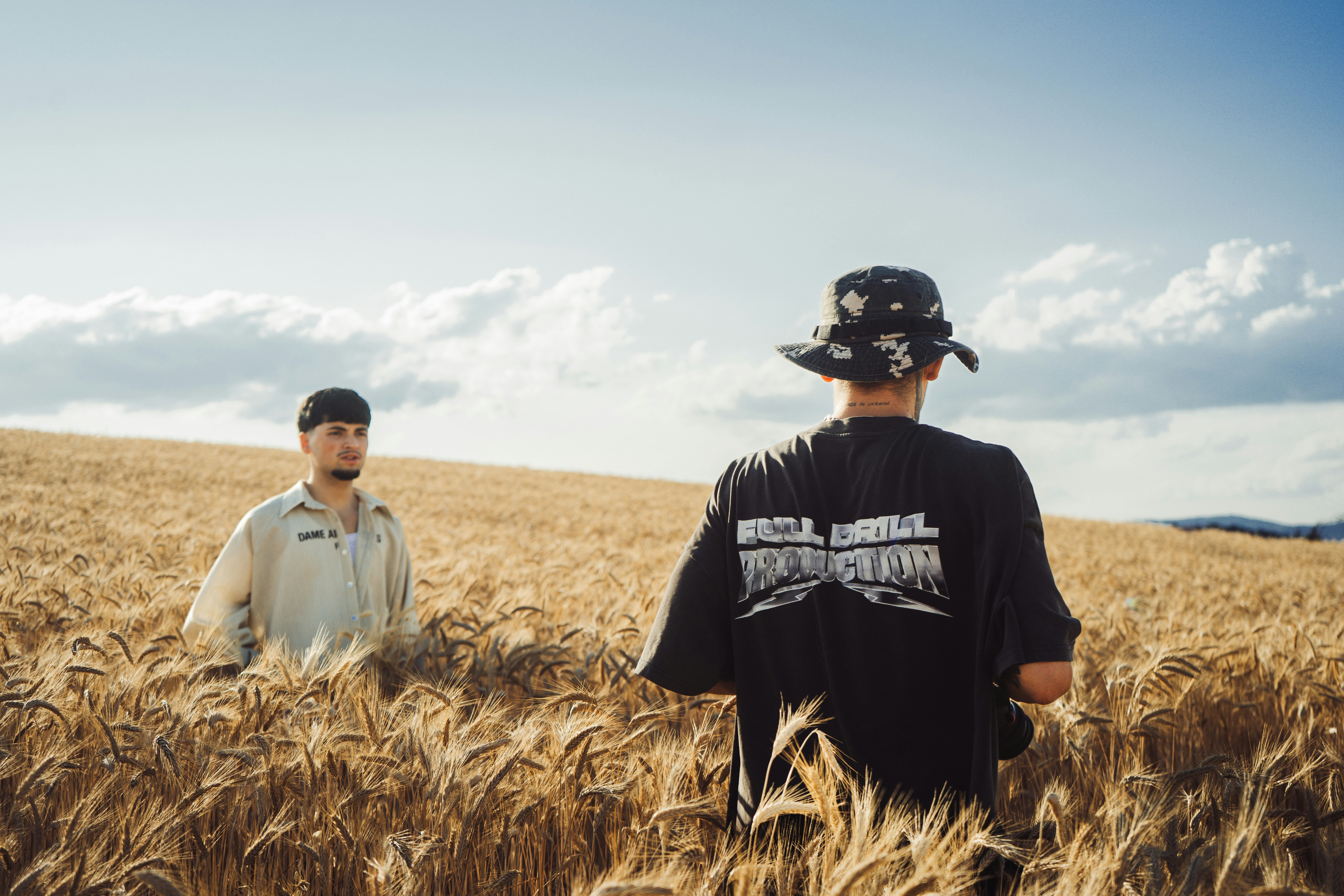 Two men walking through a golden wheat field.