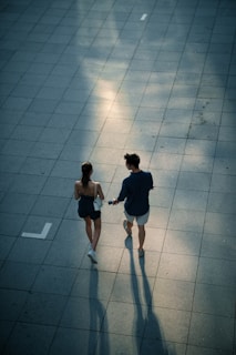 Couple walking hand in hand on a tiled path.