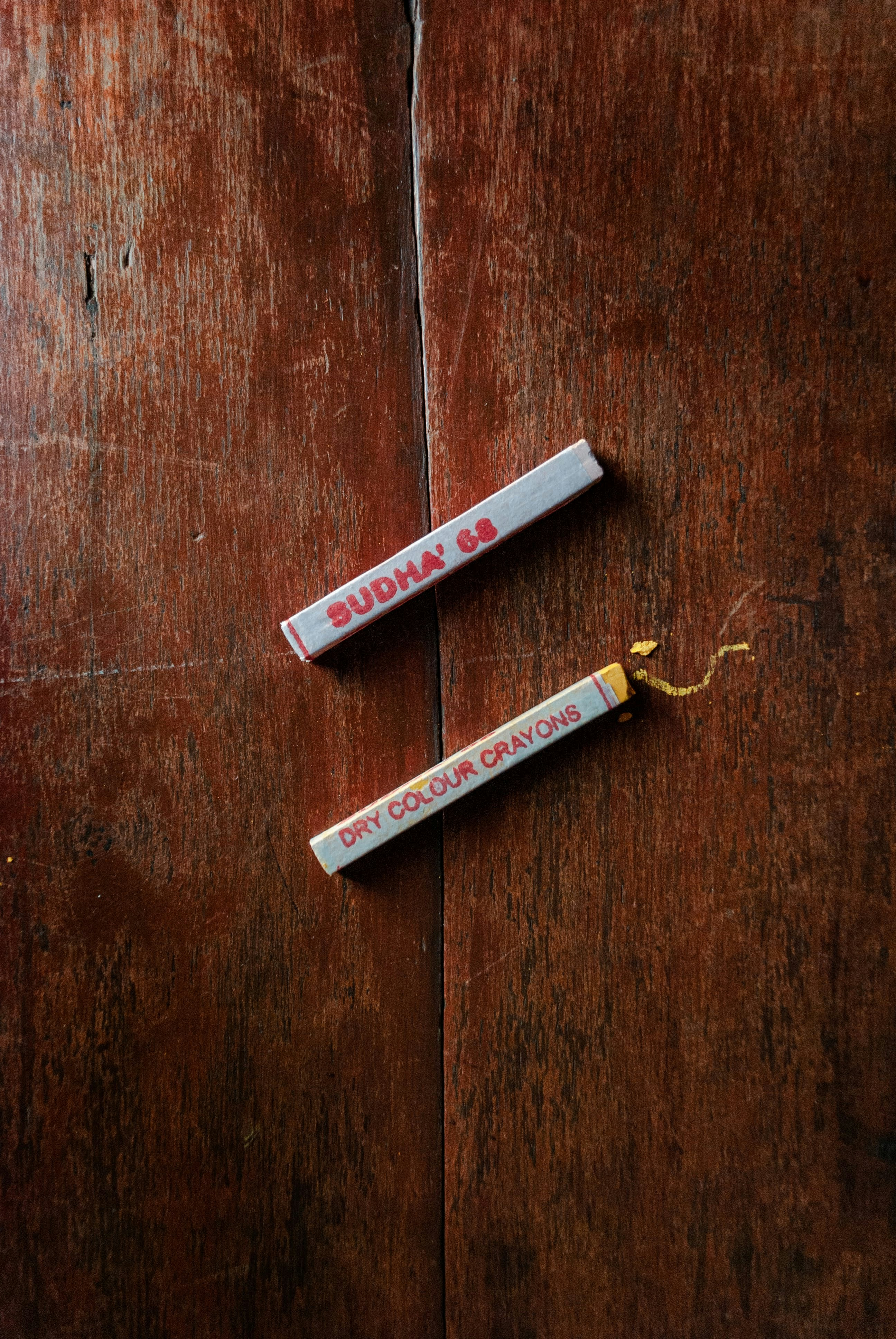 Two dry color crayons on a wooden surface