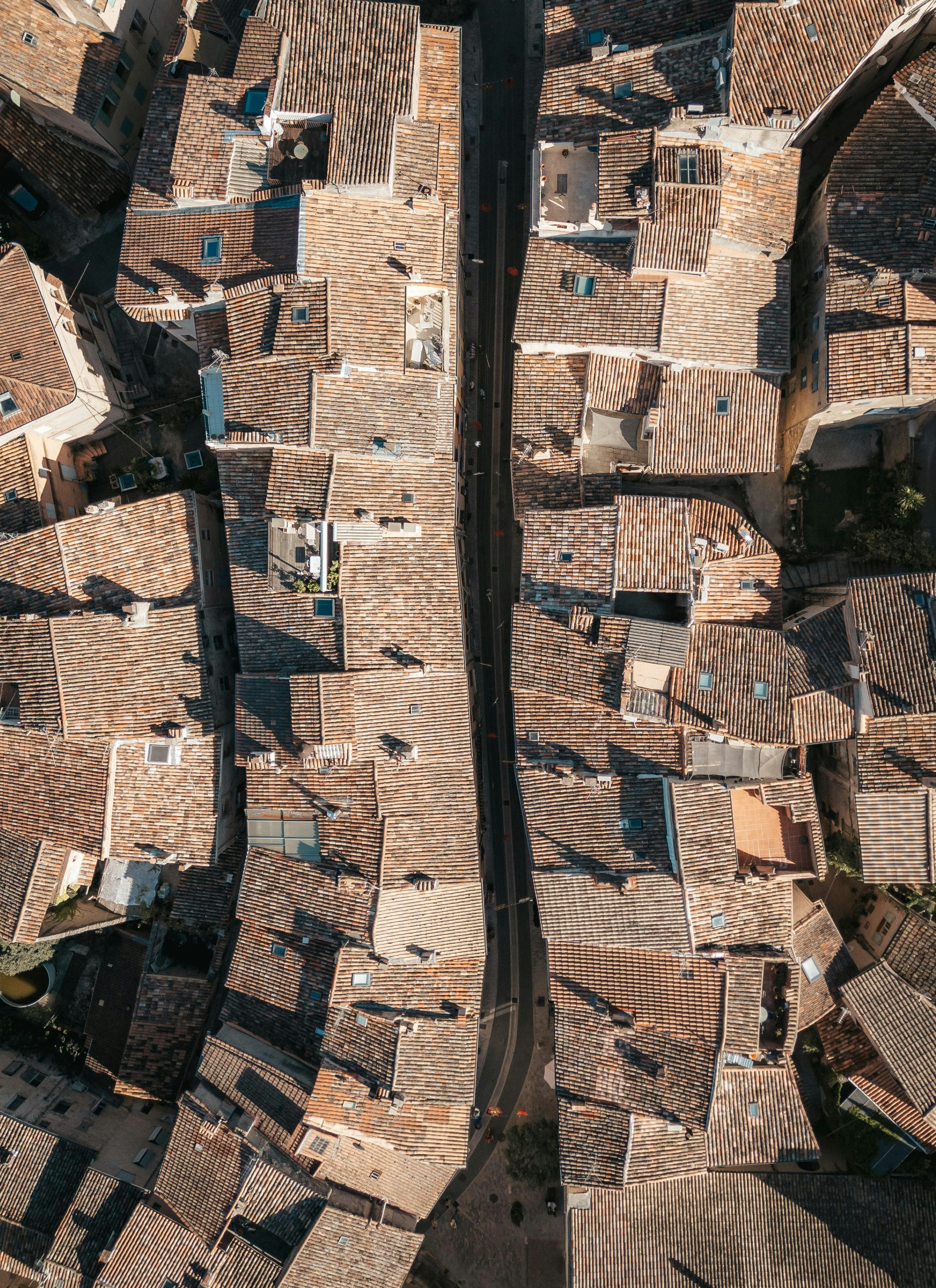 Aerial view of a narrow street lined with tiled roofs.