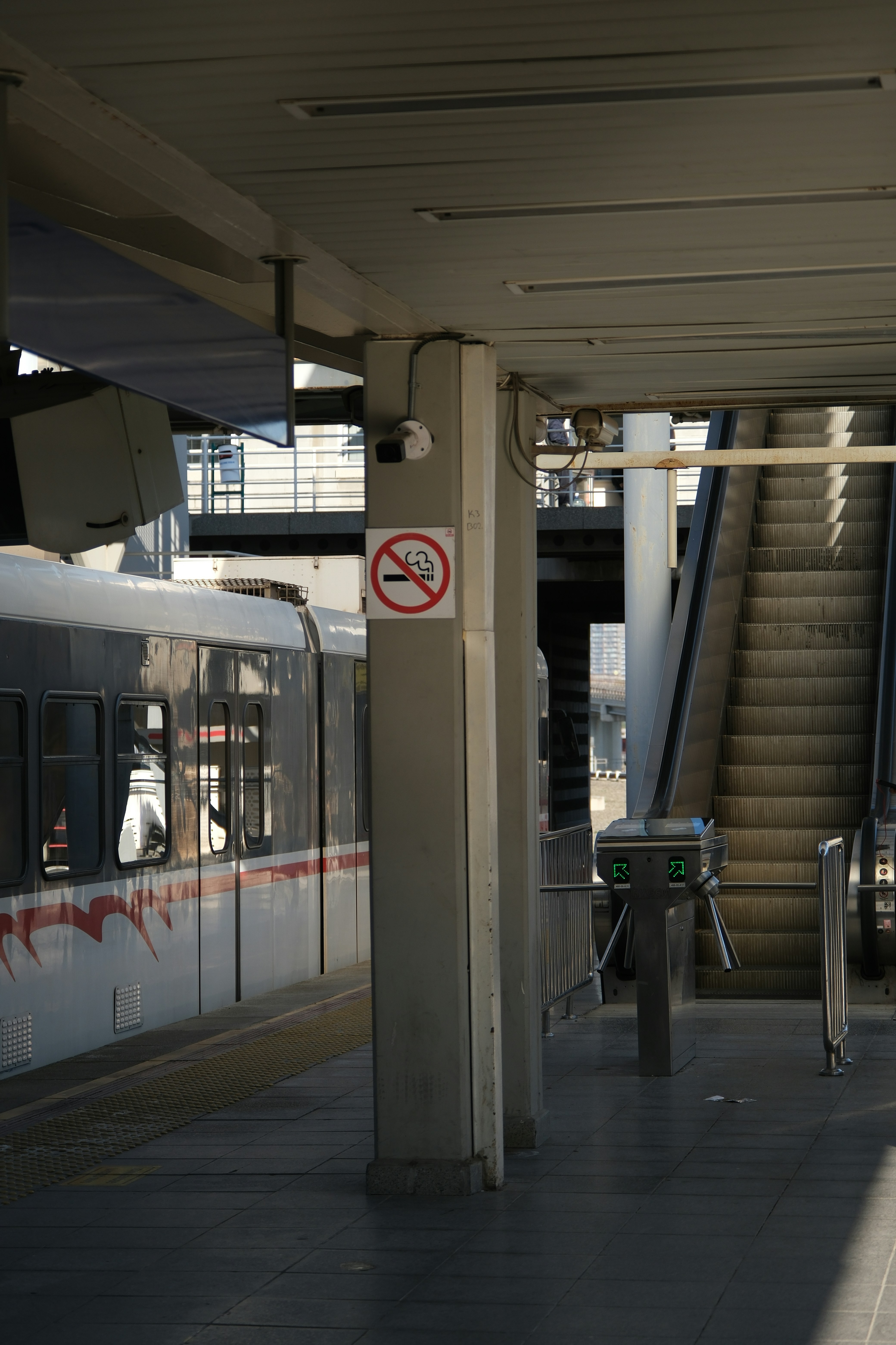 Train station with escalator and no smoking sign.