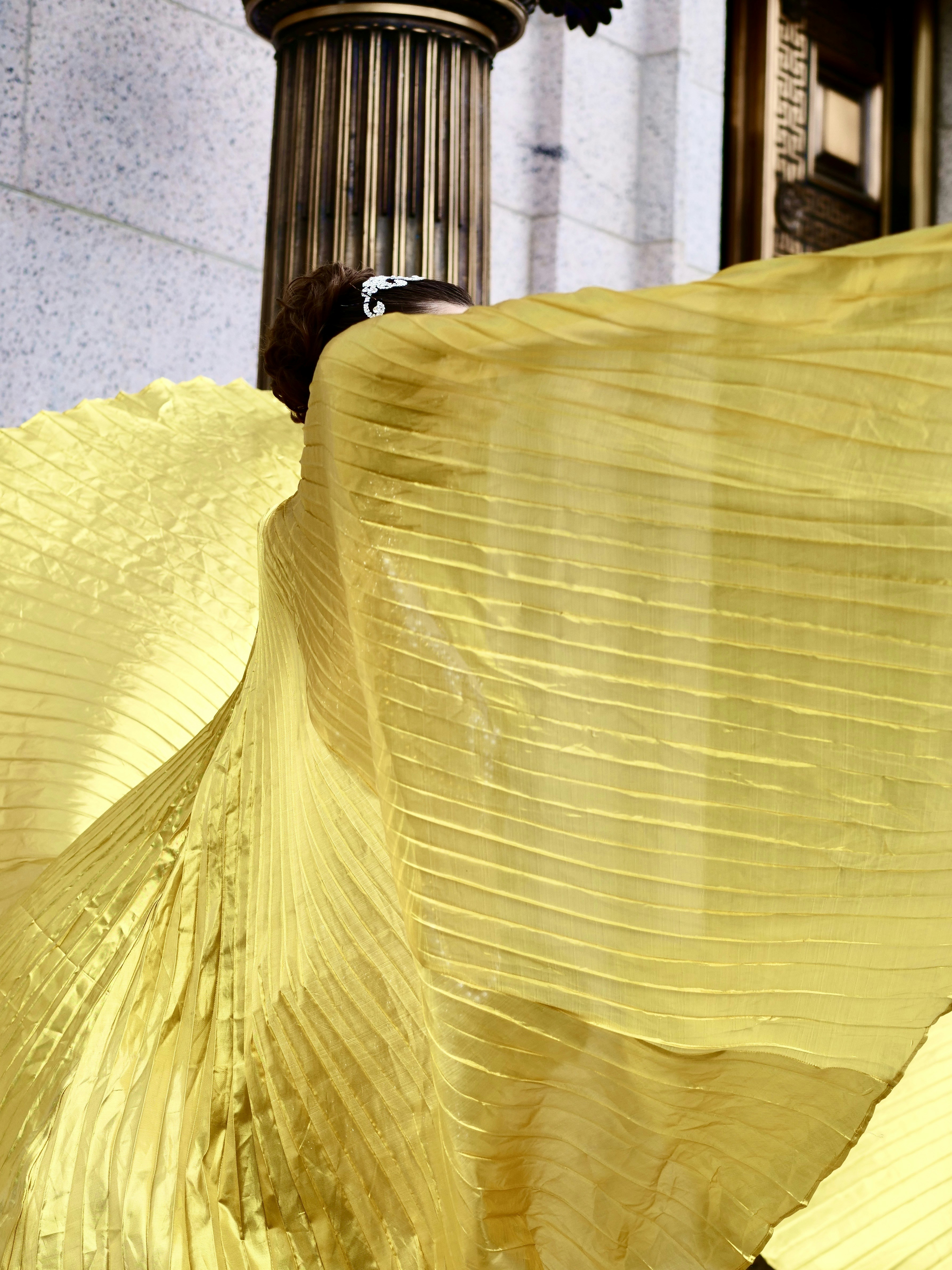 Woman in flowing yellow dress near column