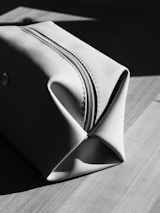 A light-colored toiletry bag on a wooden surface.