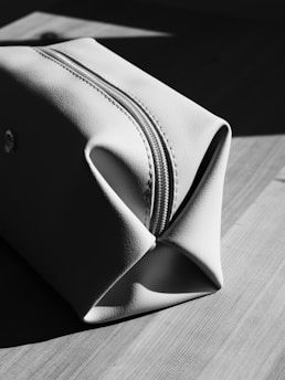 A light-colored toiletry bag on a wooden surface.