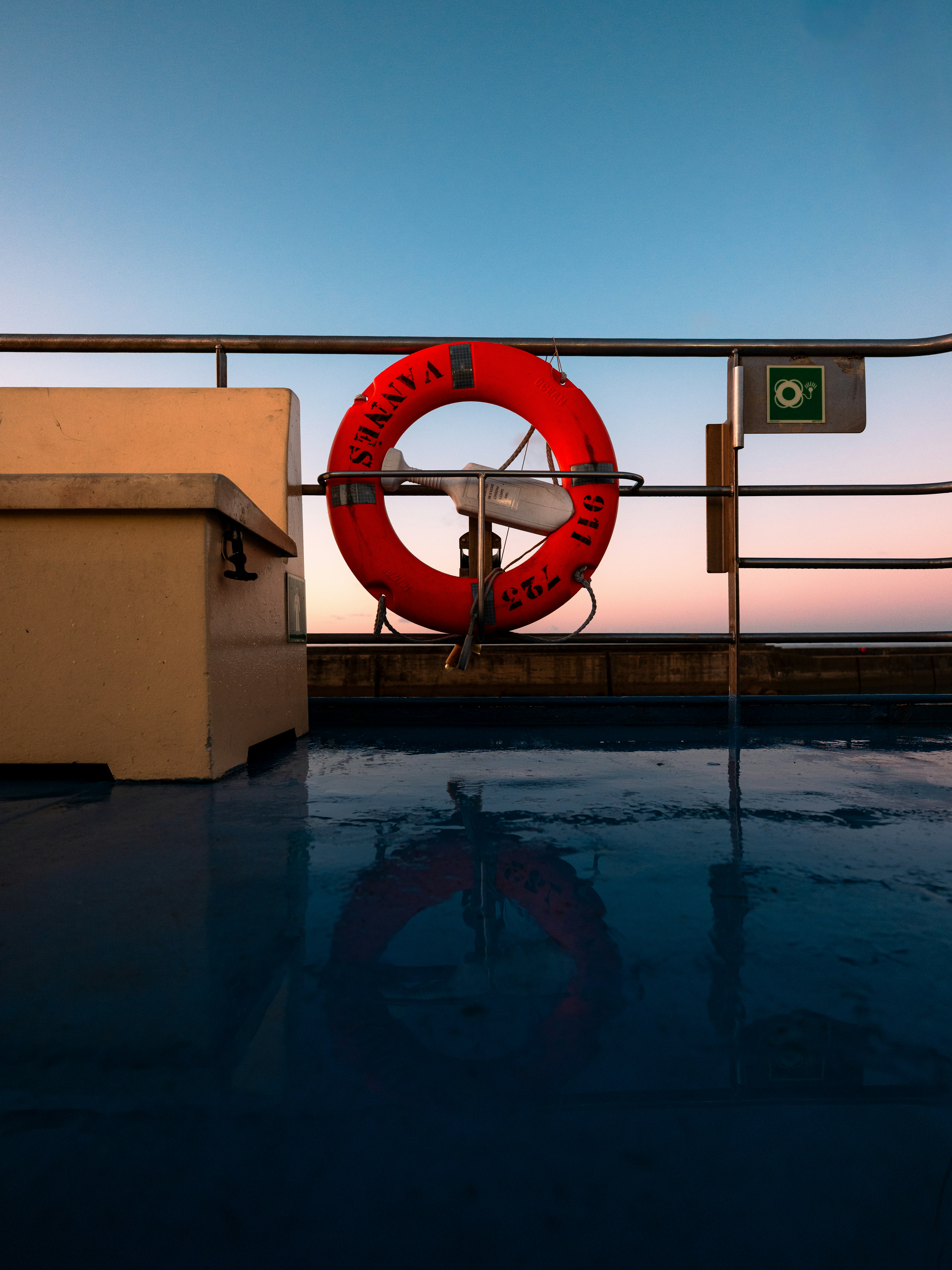 Orange life preserver on a ship deck at sunset.