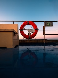 Orange life preserver on a ship deck at sunset.