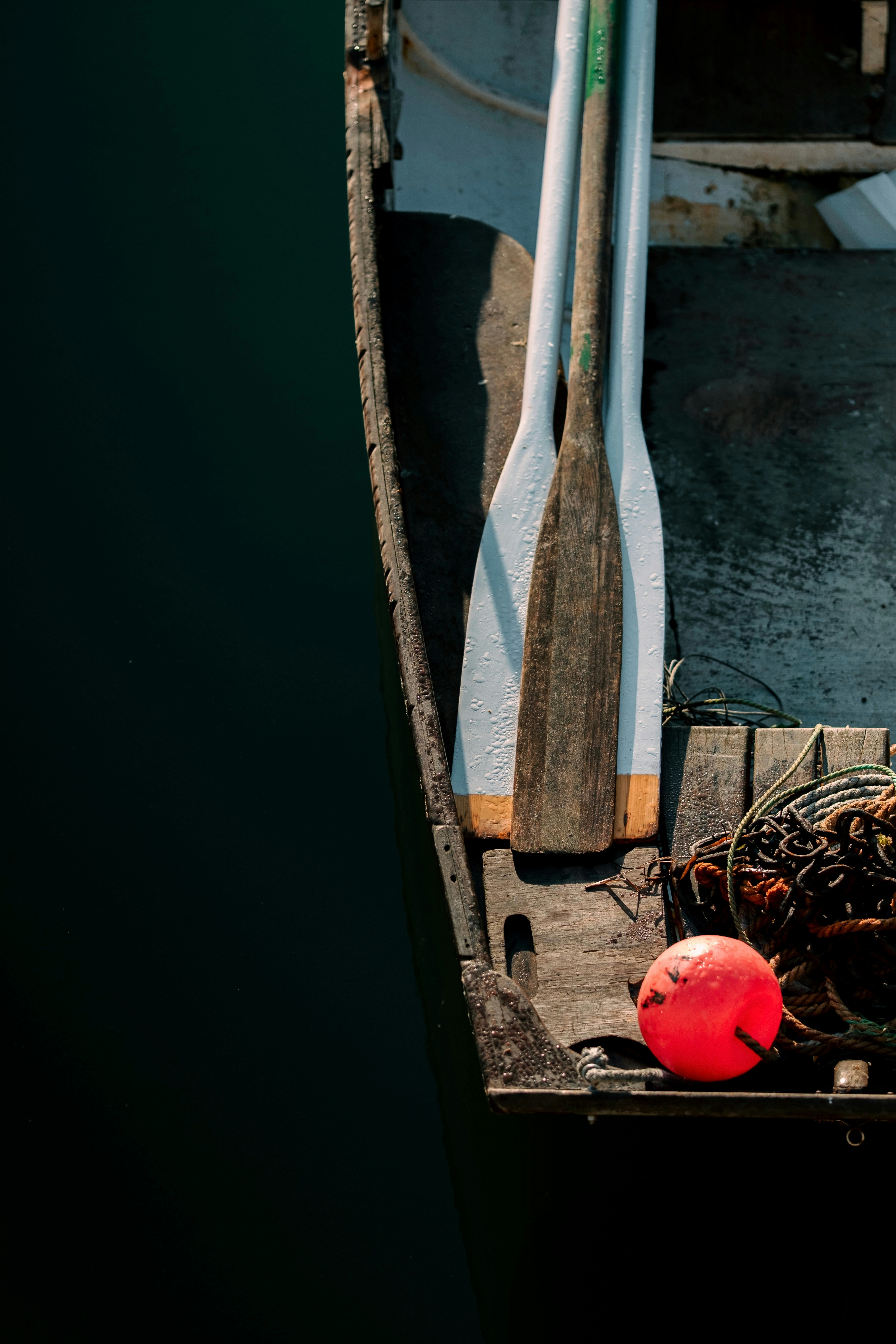 Two oars and a red buoy in a weathered rowboat