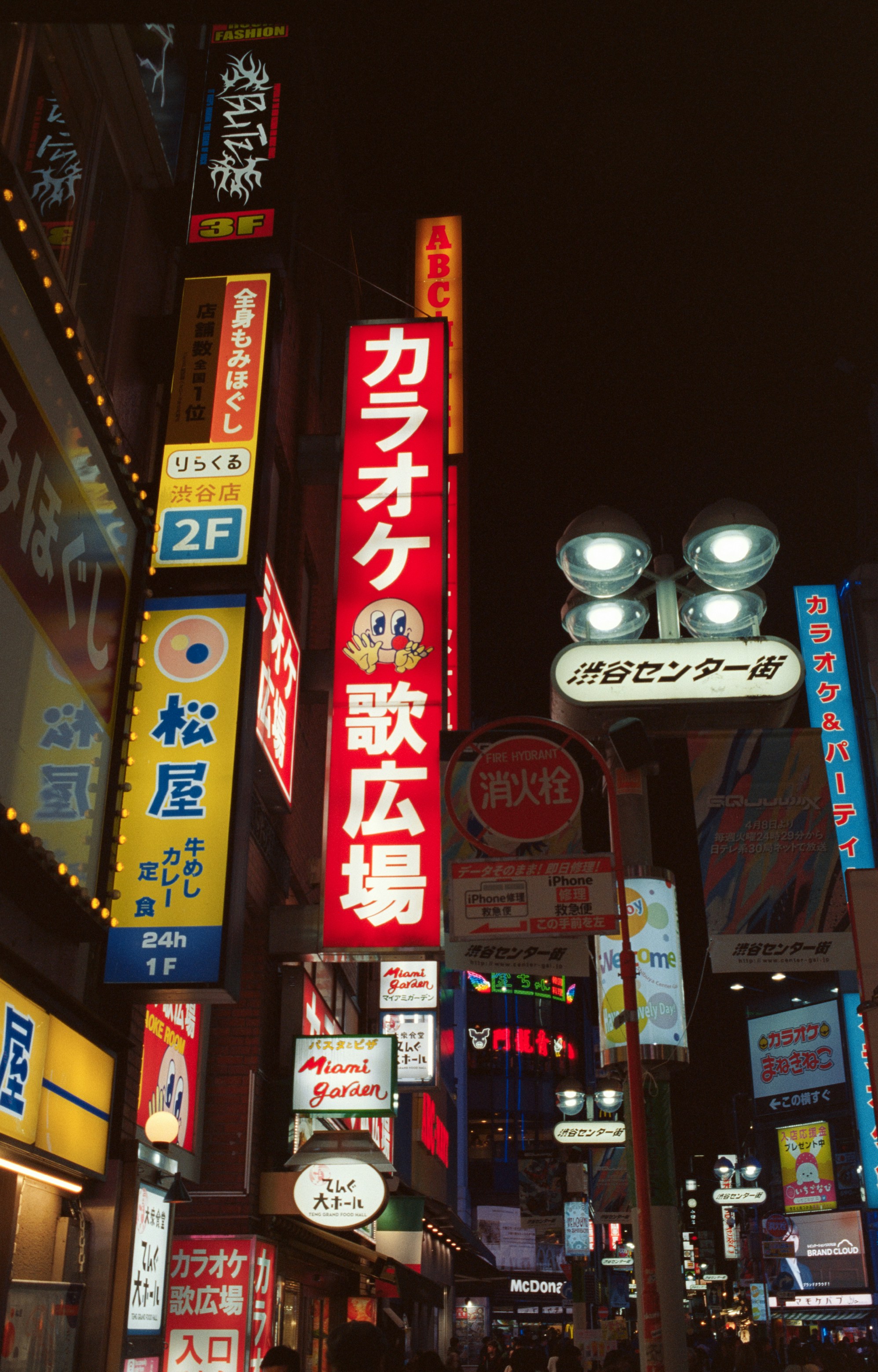 Bright neon signs illuminate a city street at night.