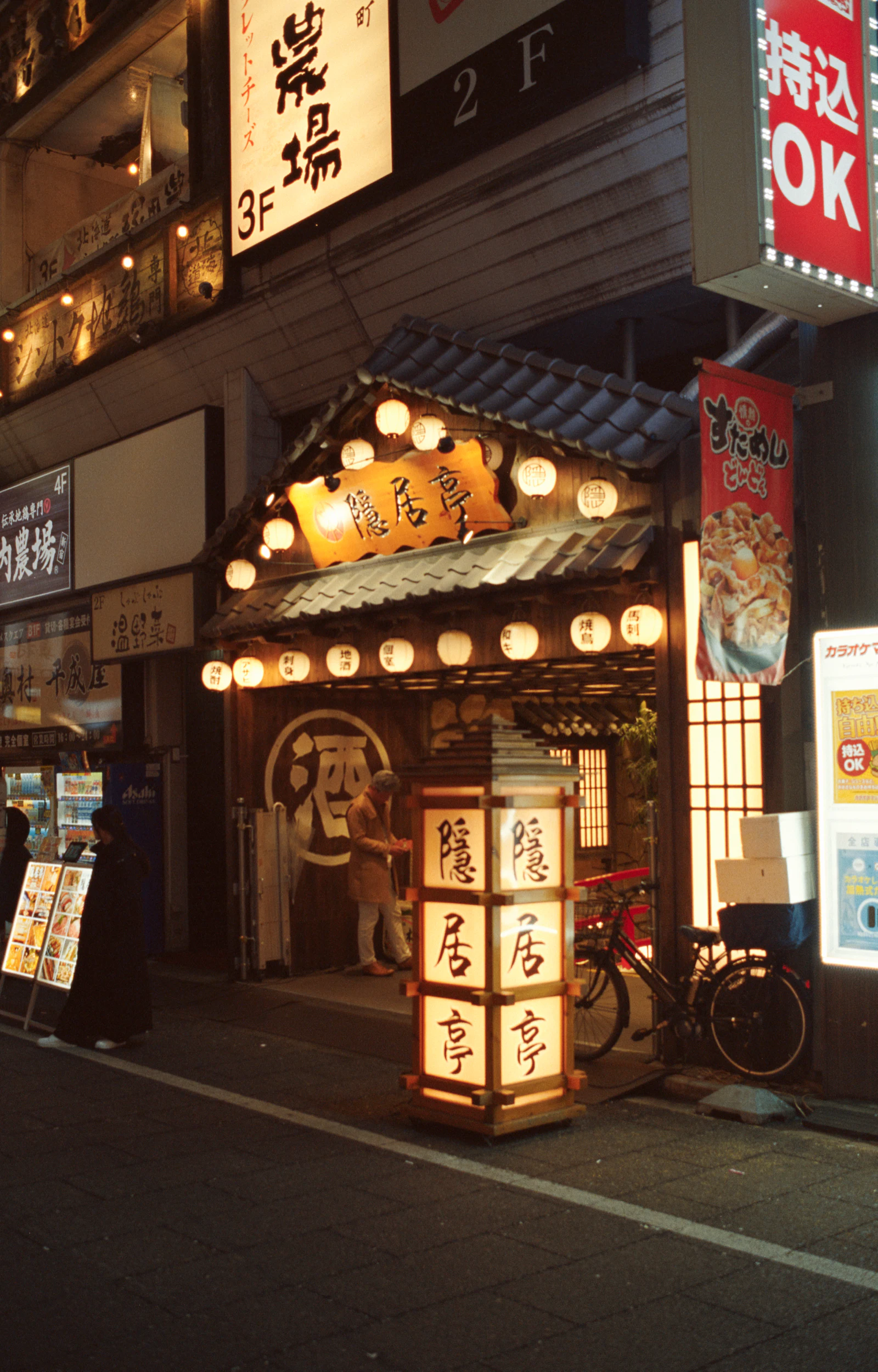 夜の居酒屋の入口。提灯の灯りが路地を照らす様子