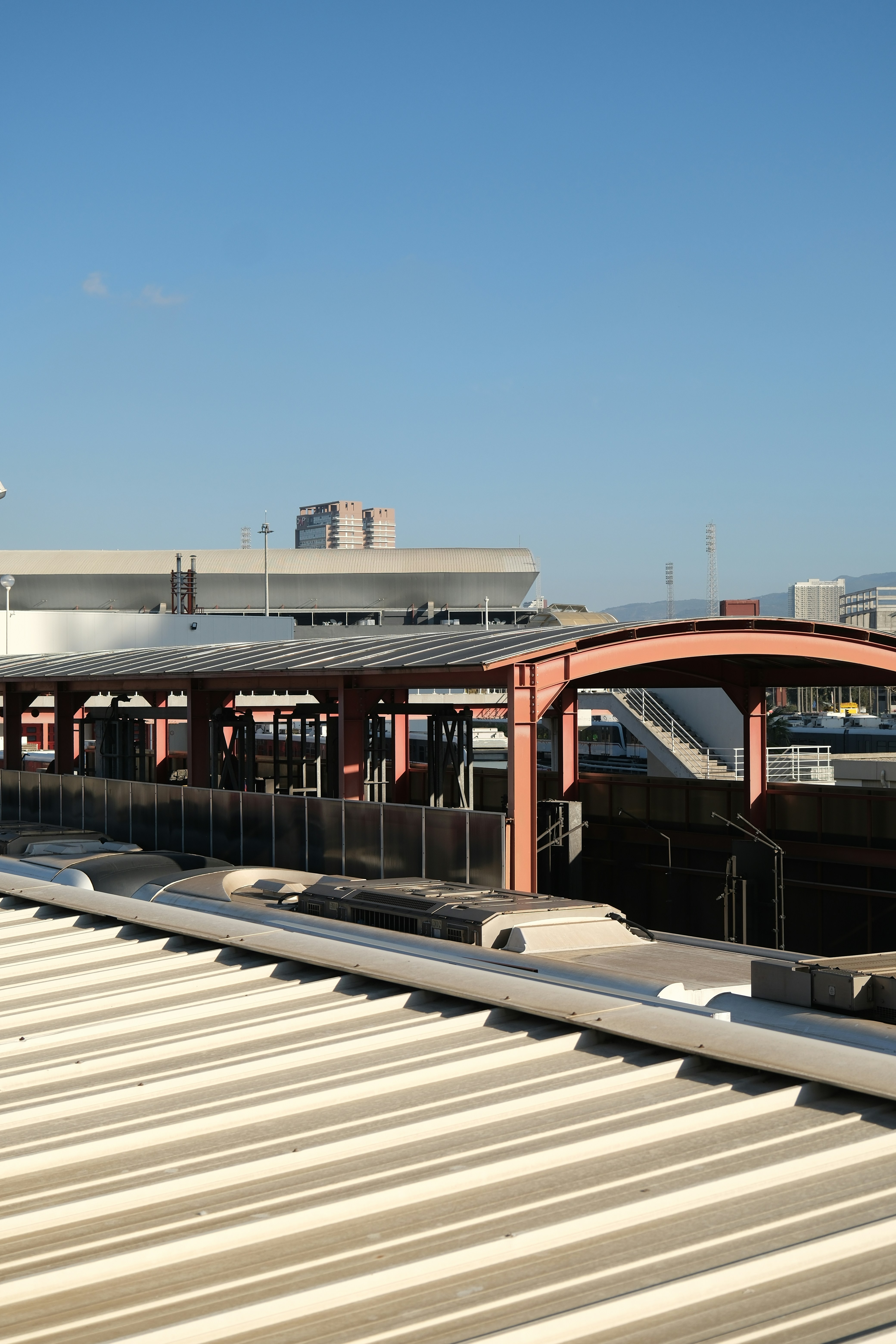 Train station platform with covered waiting area and buildings.