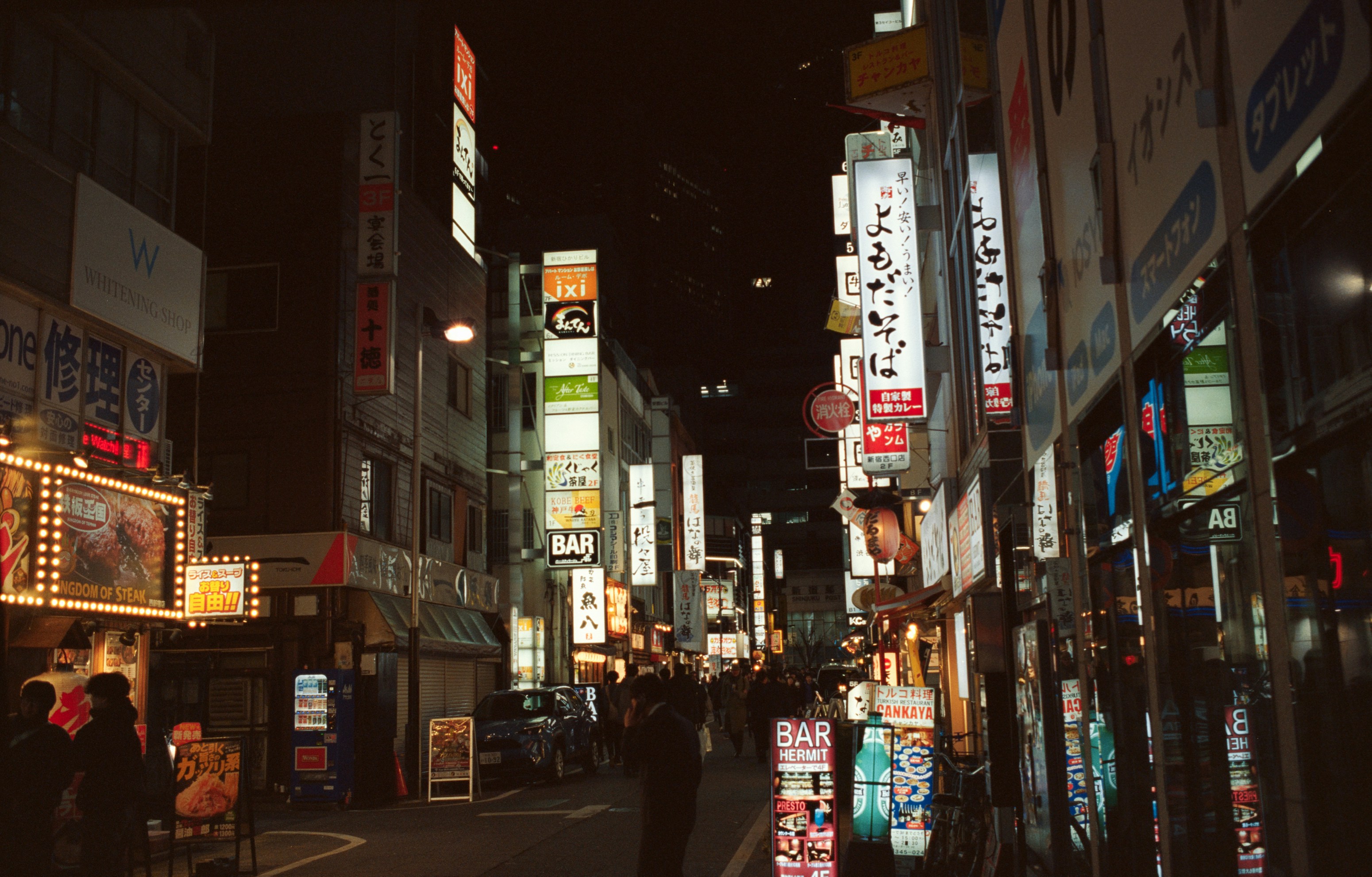 Street scene with glowing signs at night.