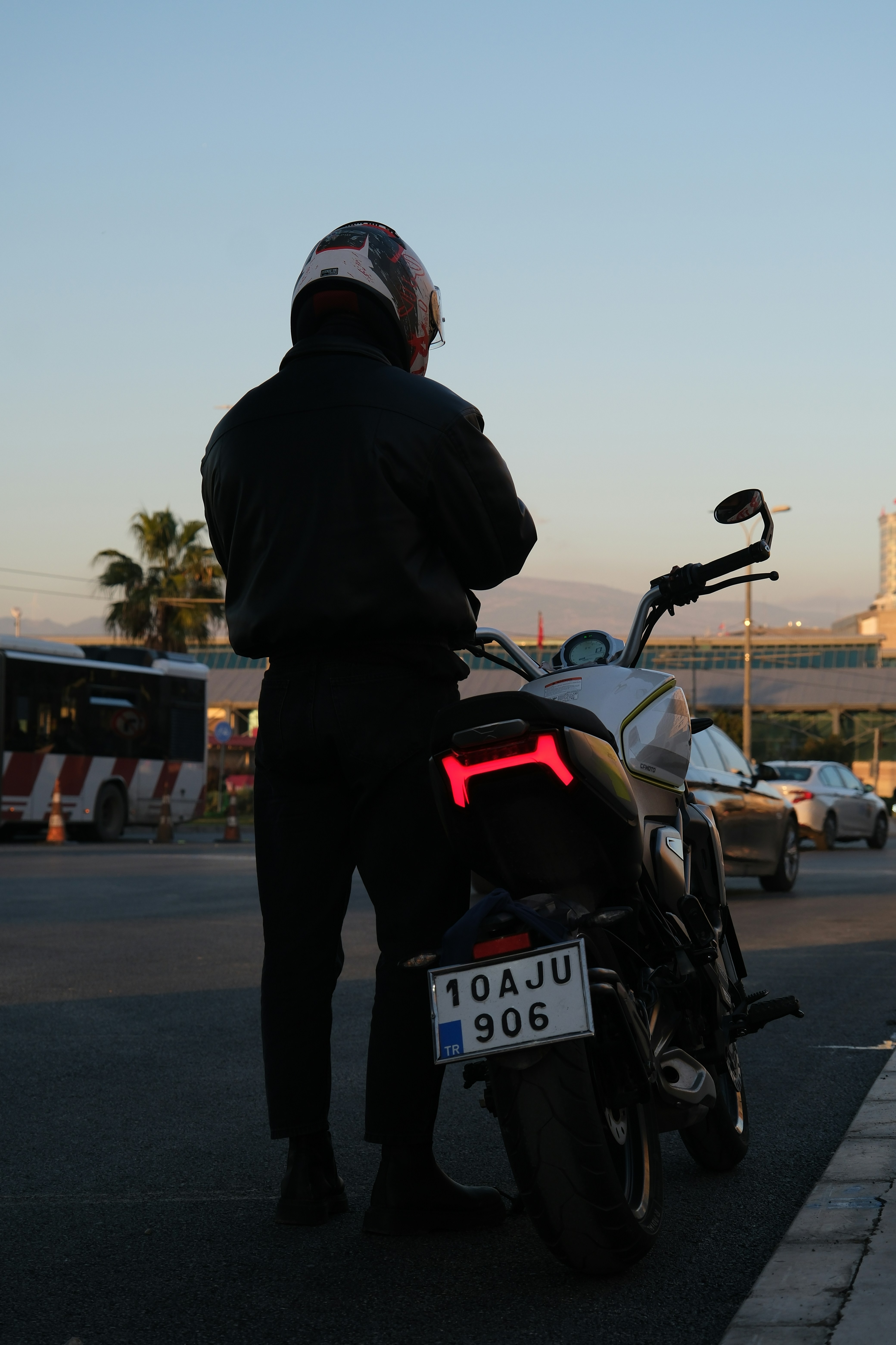 Helmeted motorcycle rider standing beside a motorcycle in an urban environment