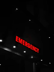 Red emergency sign illuminates a dark building entrance.
