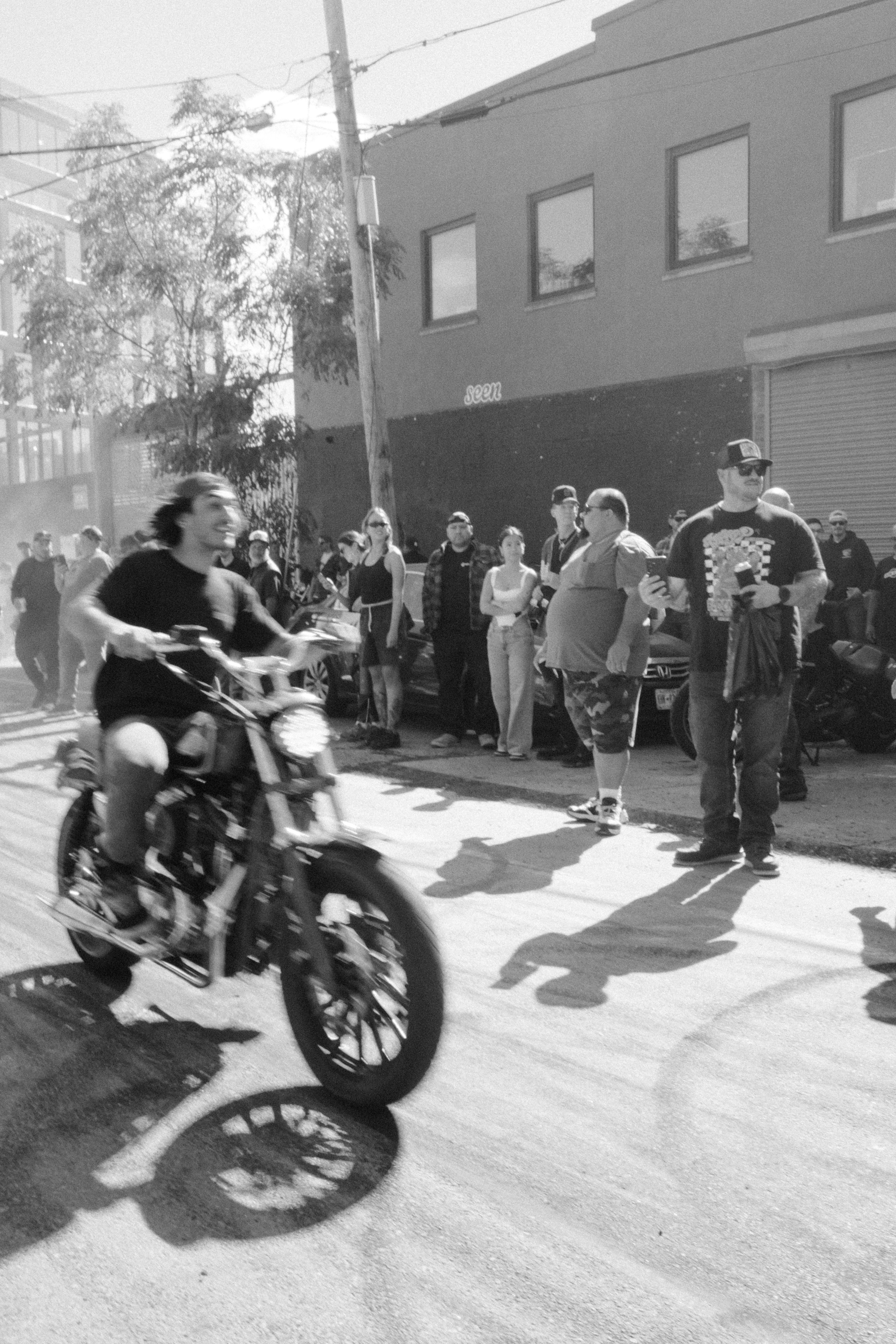 Man riding a motorcycle down a street with onlookers