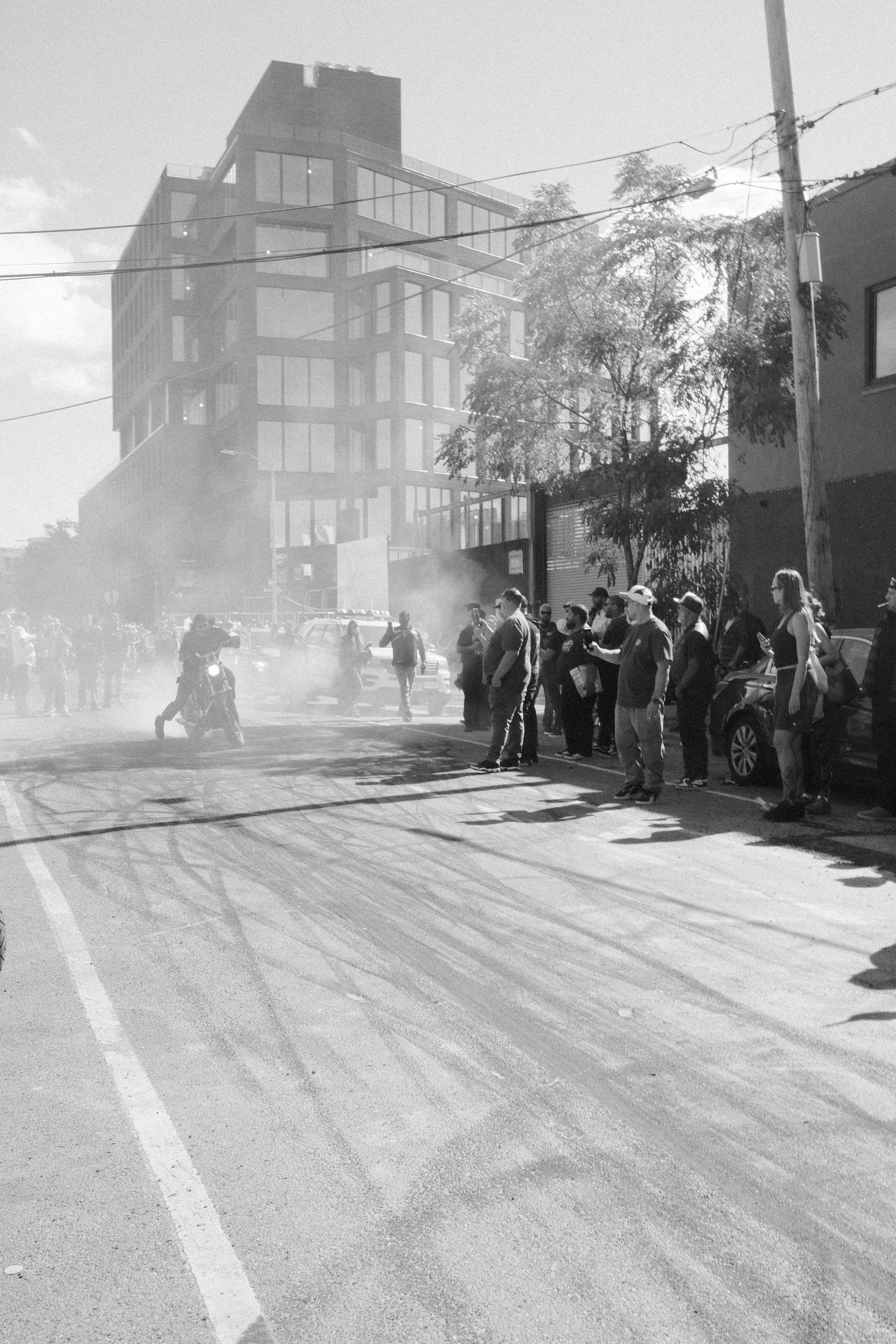 Motorcyclist performing burnout in smoky street with onlookers