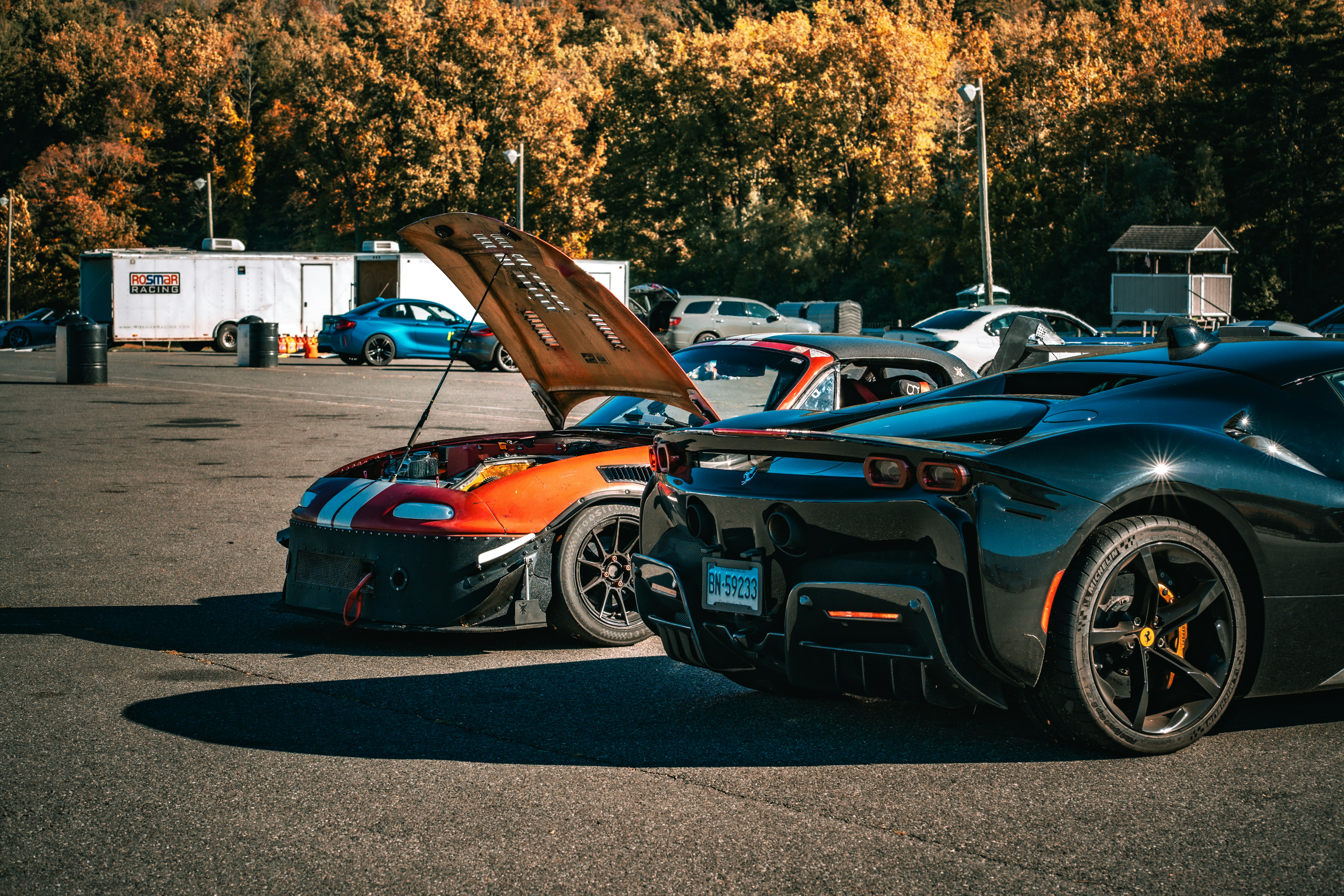 Two sports cars parked with hoods open