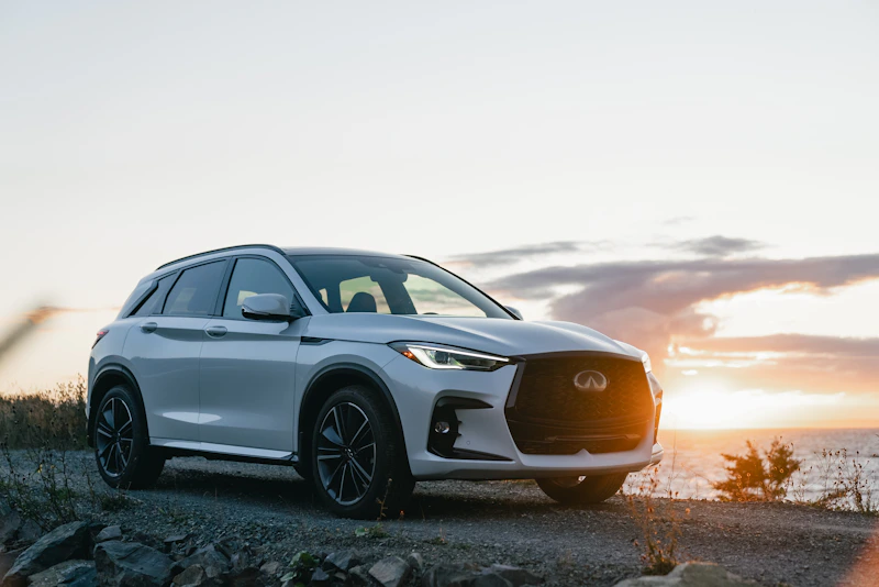 Biały SUV nad oceanem o zachodzie słońca – styl życia premium