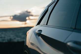 Car parked by the ocean at sunset
