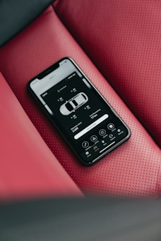 Smartphone displaying car app on red leather seat