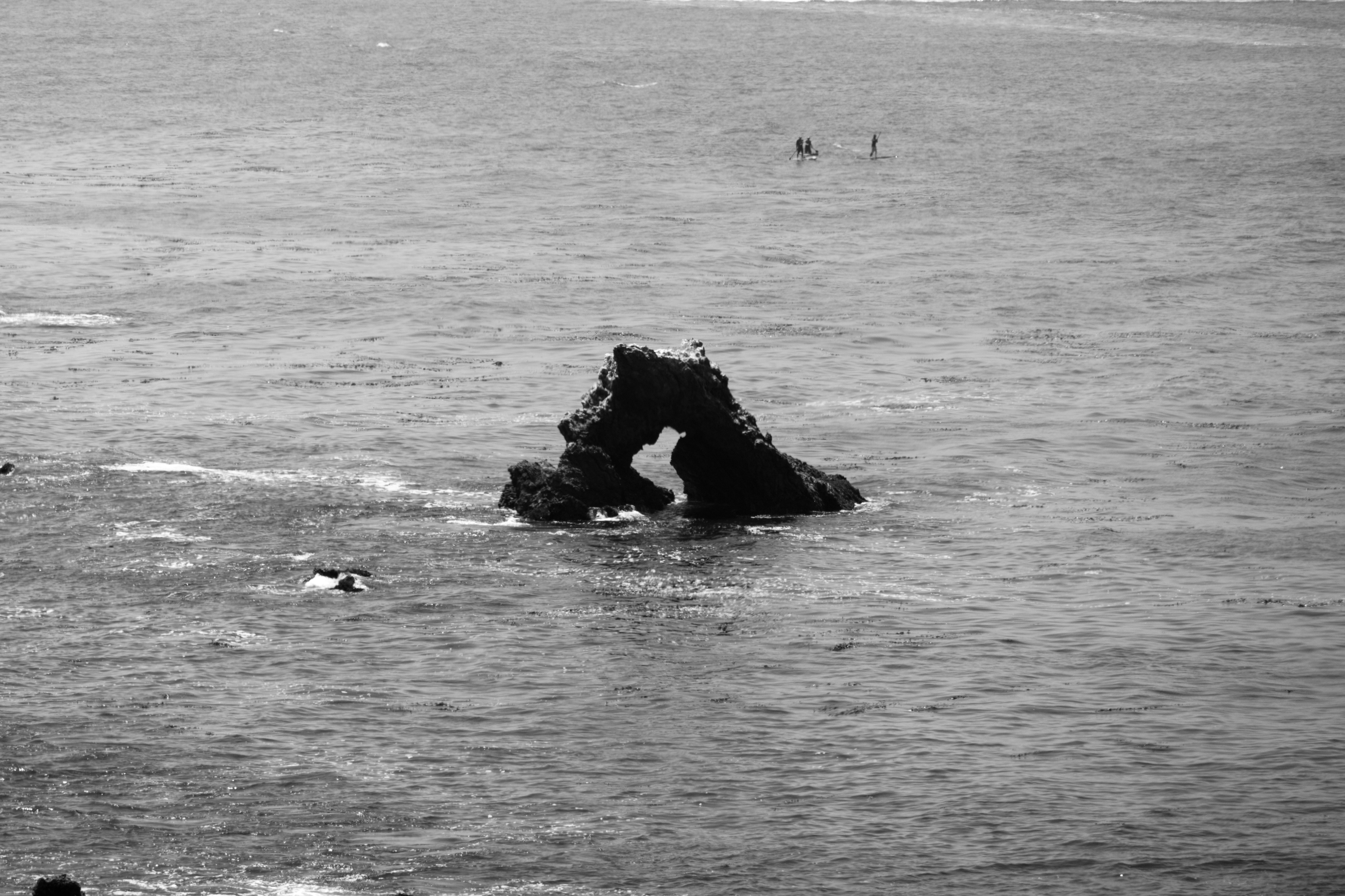 Rock arch formation in the ocean with swimmers.