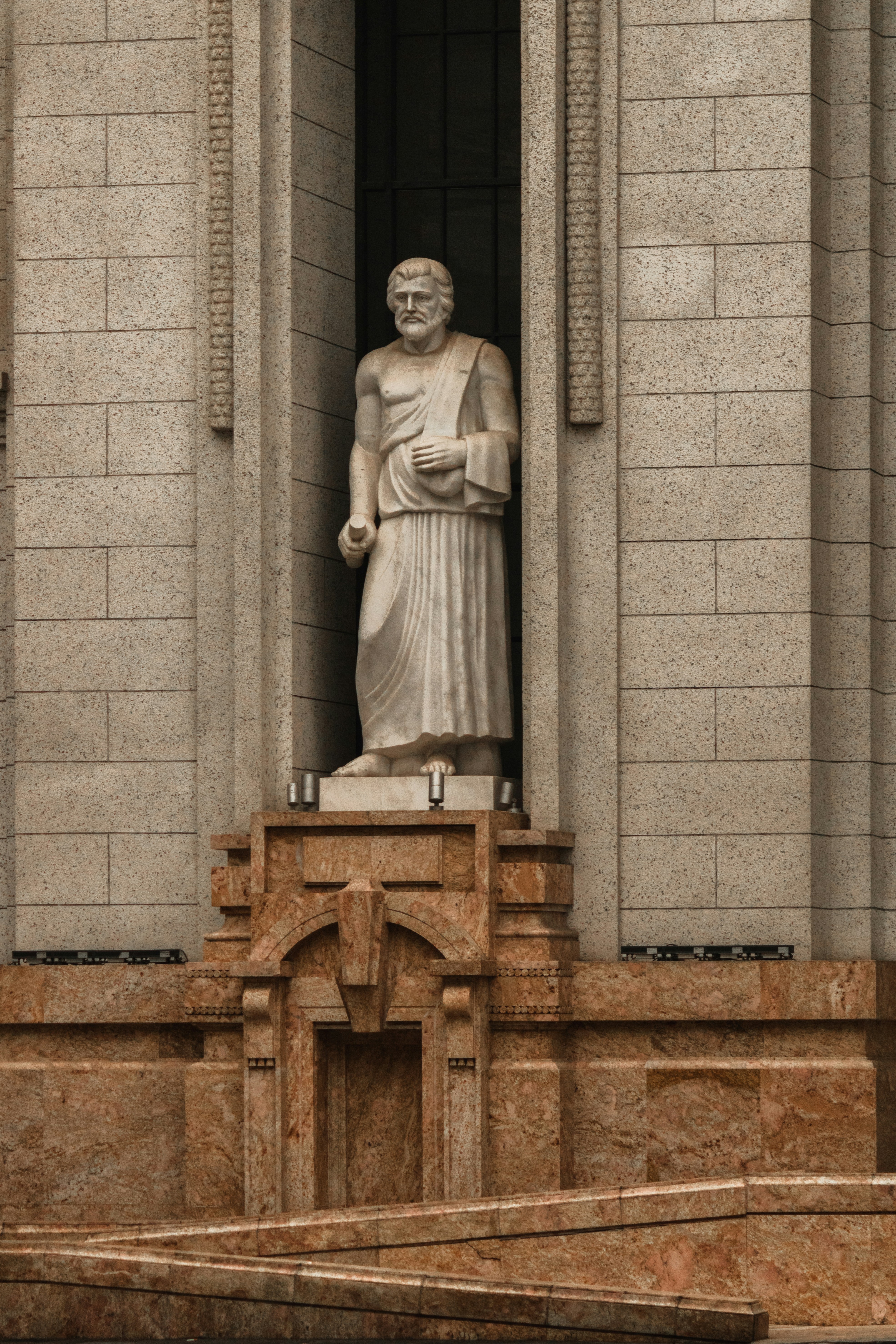 Stone statue of a robed man in architectural niche