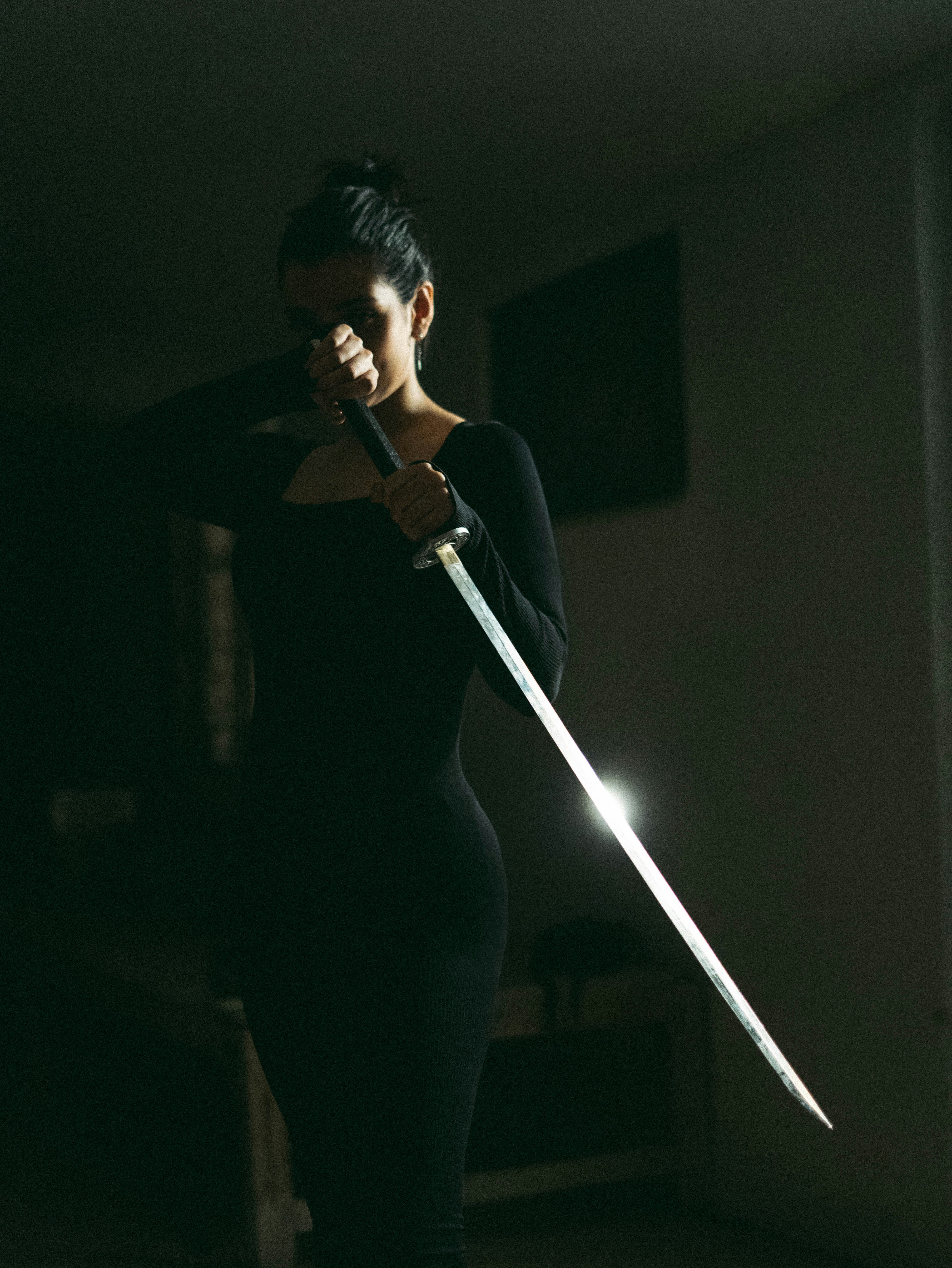 Woman in black dress holding a katana sword.
