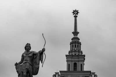Statue of a man with bow and arrow, building spire.