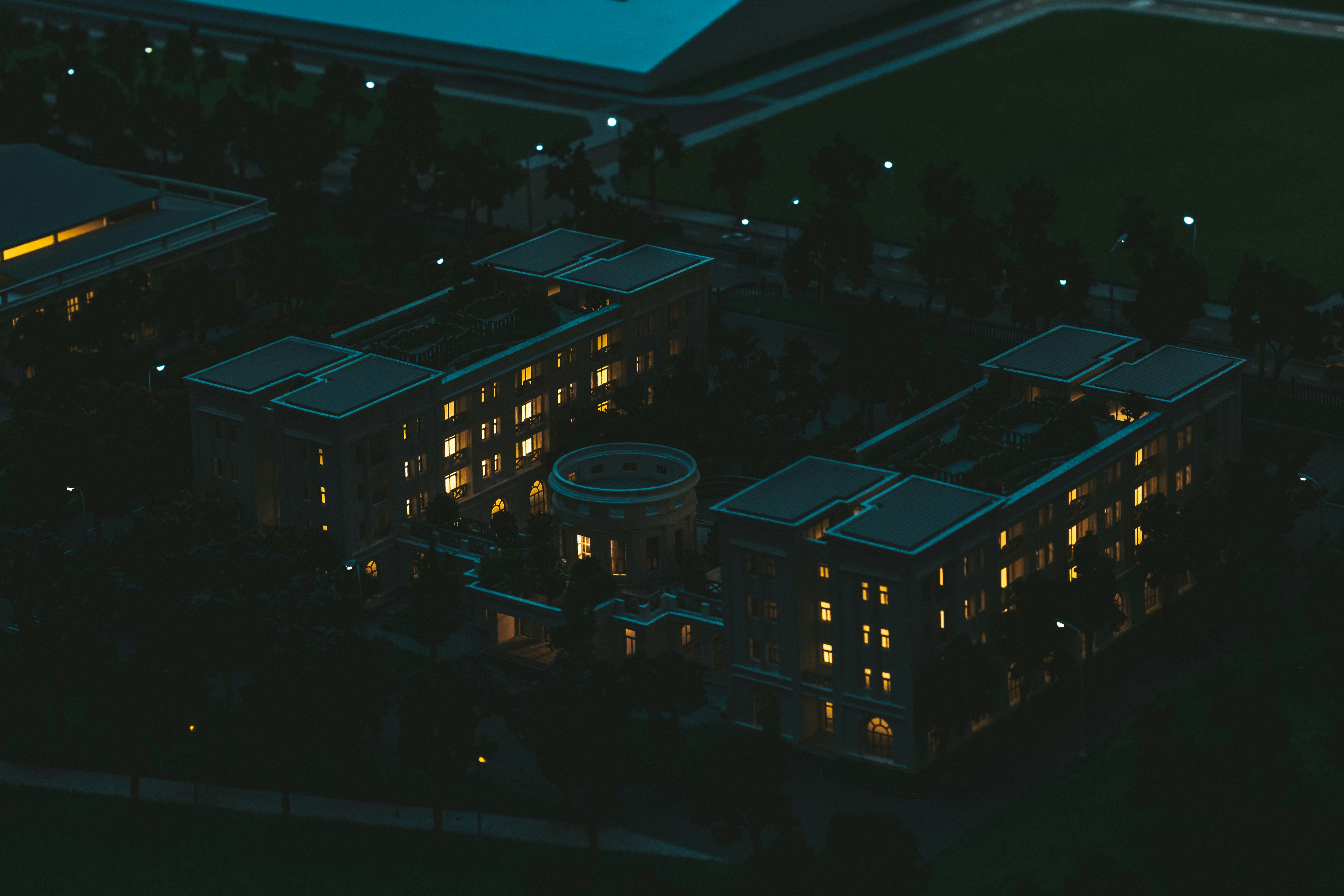 Illuminated building complex at night with surrounding green space.