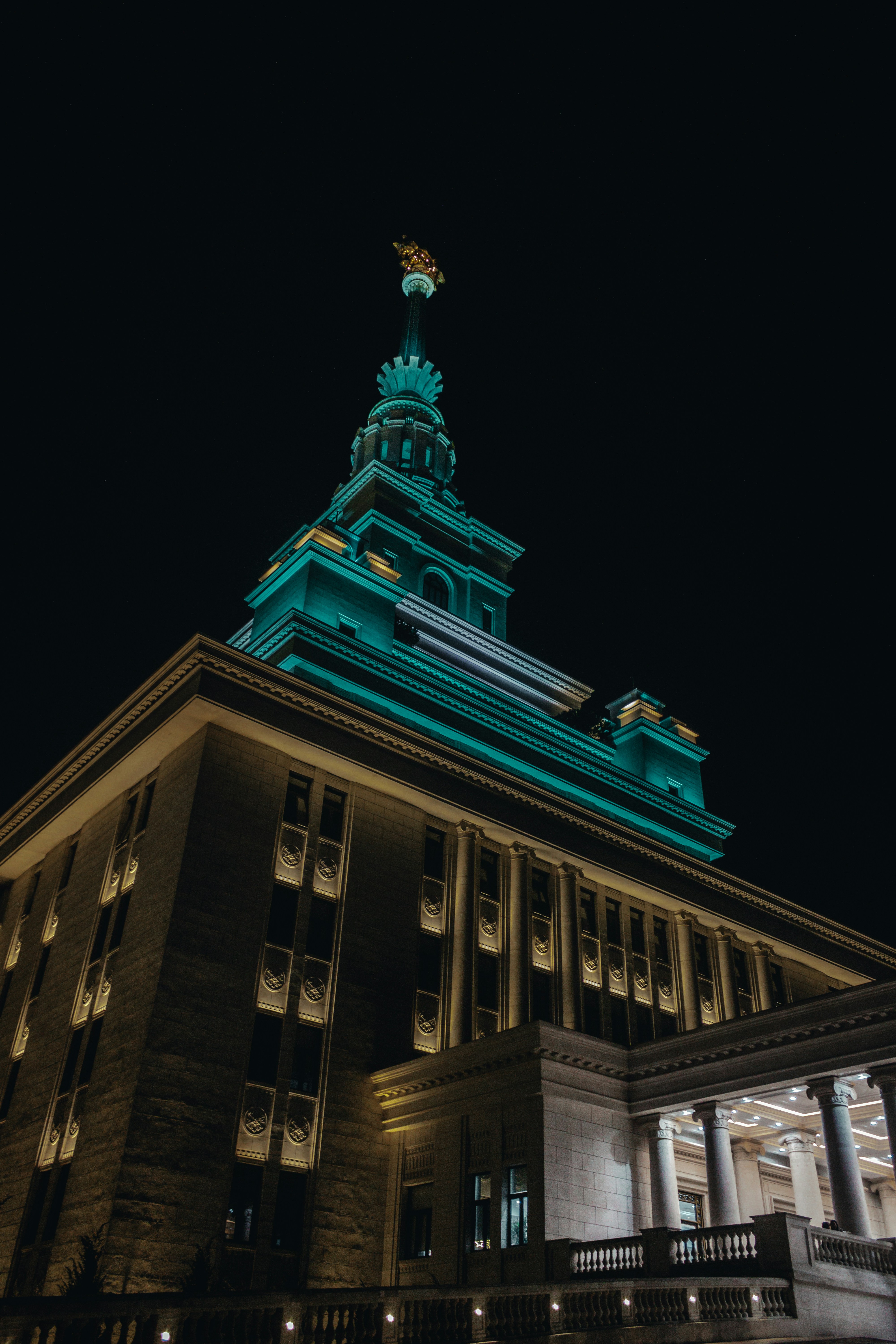 Ornate building illuminated at night with teal lighting.