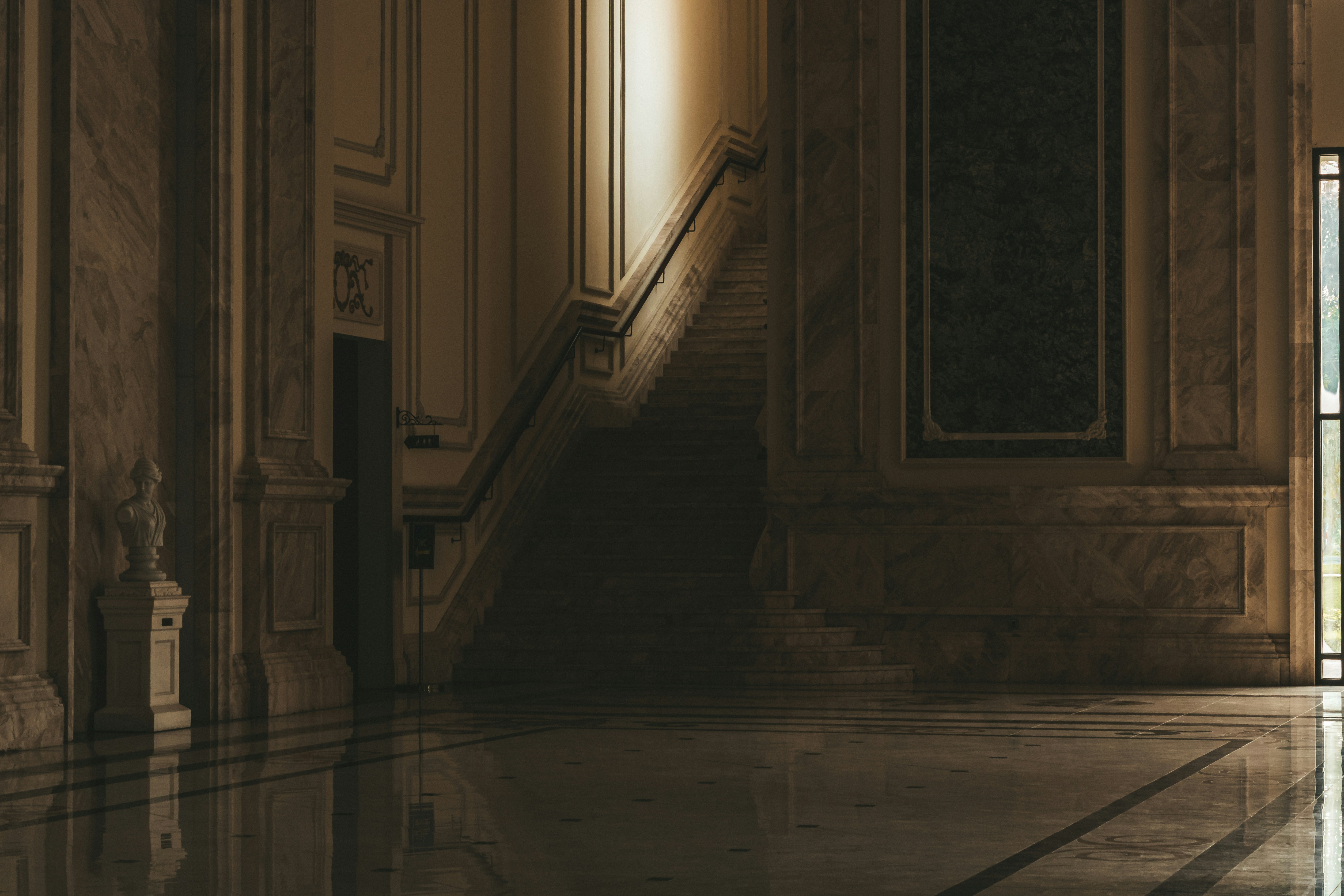 Marble staircase in a grand, dimly lit hall.