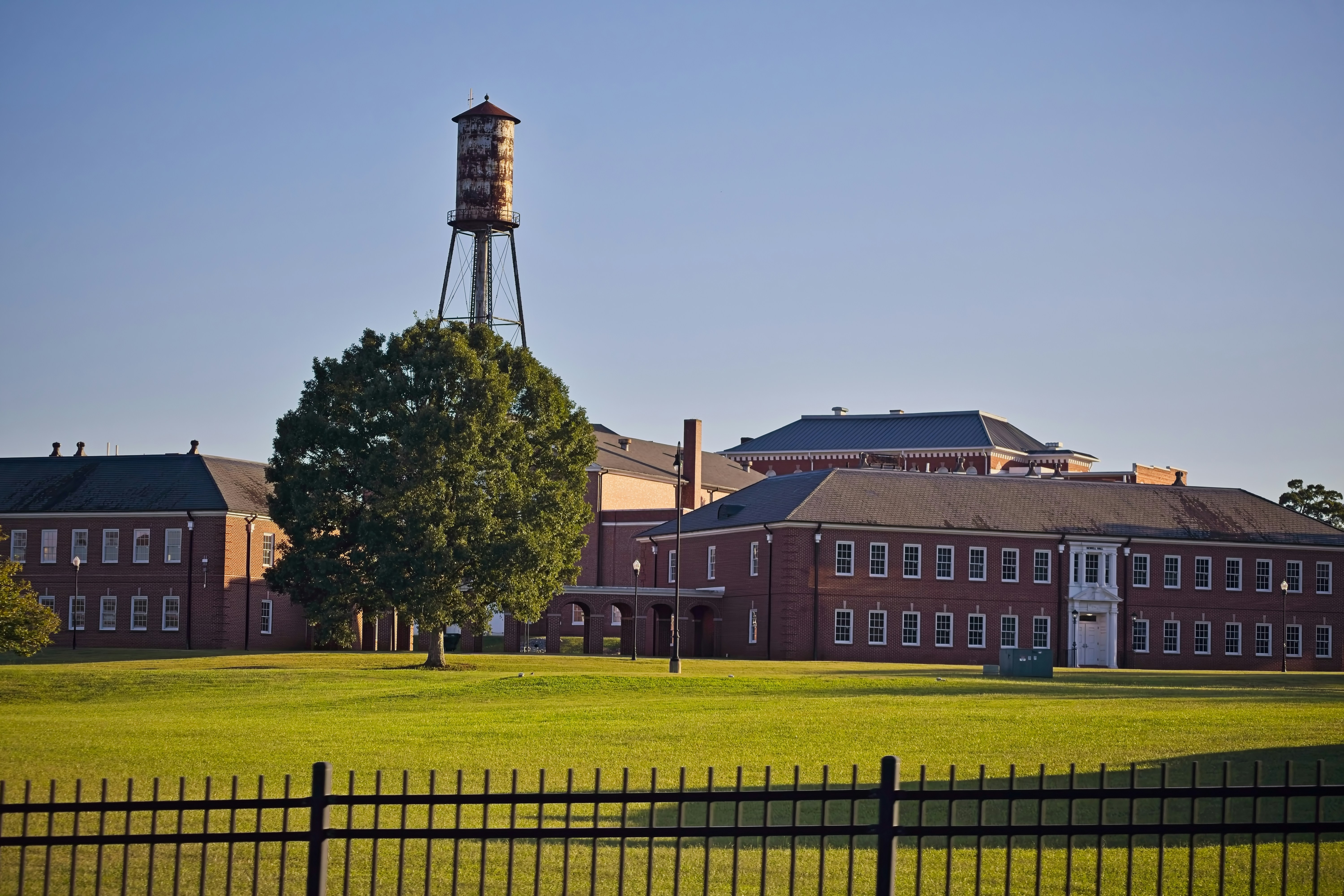 Brick building with water tower and green lawn.